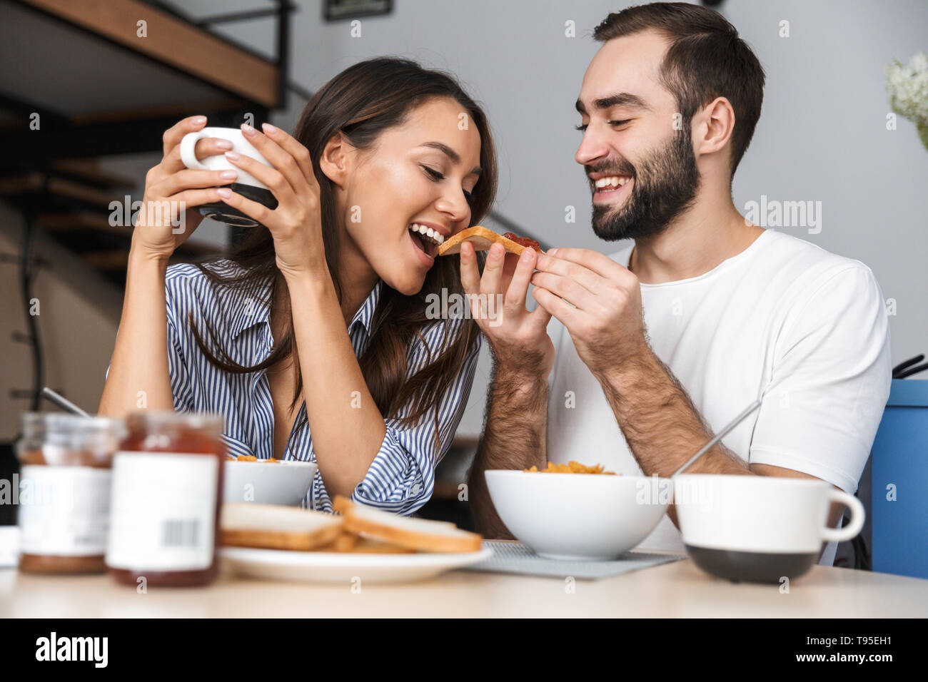 Happy multiethnic couple having breakfast at the kitchen Stock Photo
