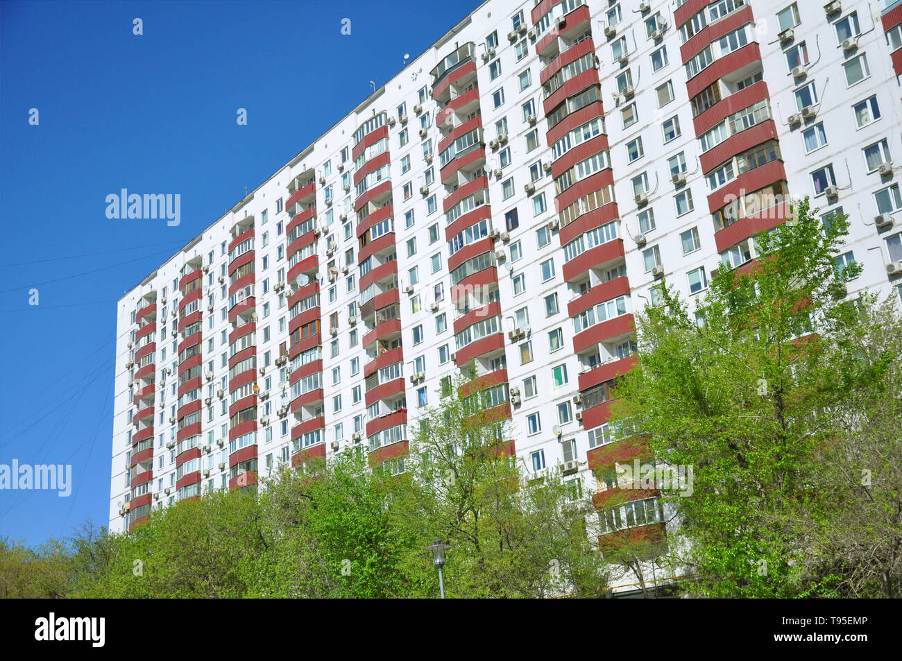 Facade of a multi-storey building. On a background of blue eb and bushes Stock Photo