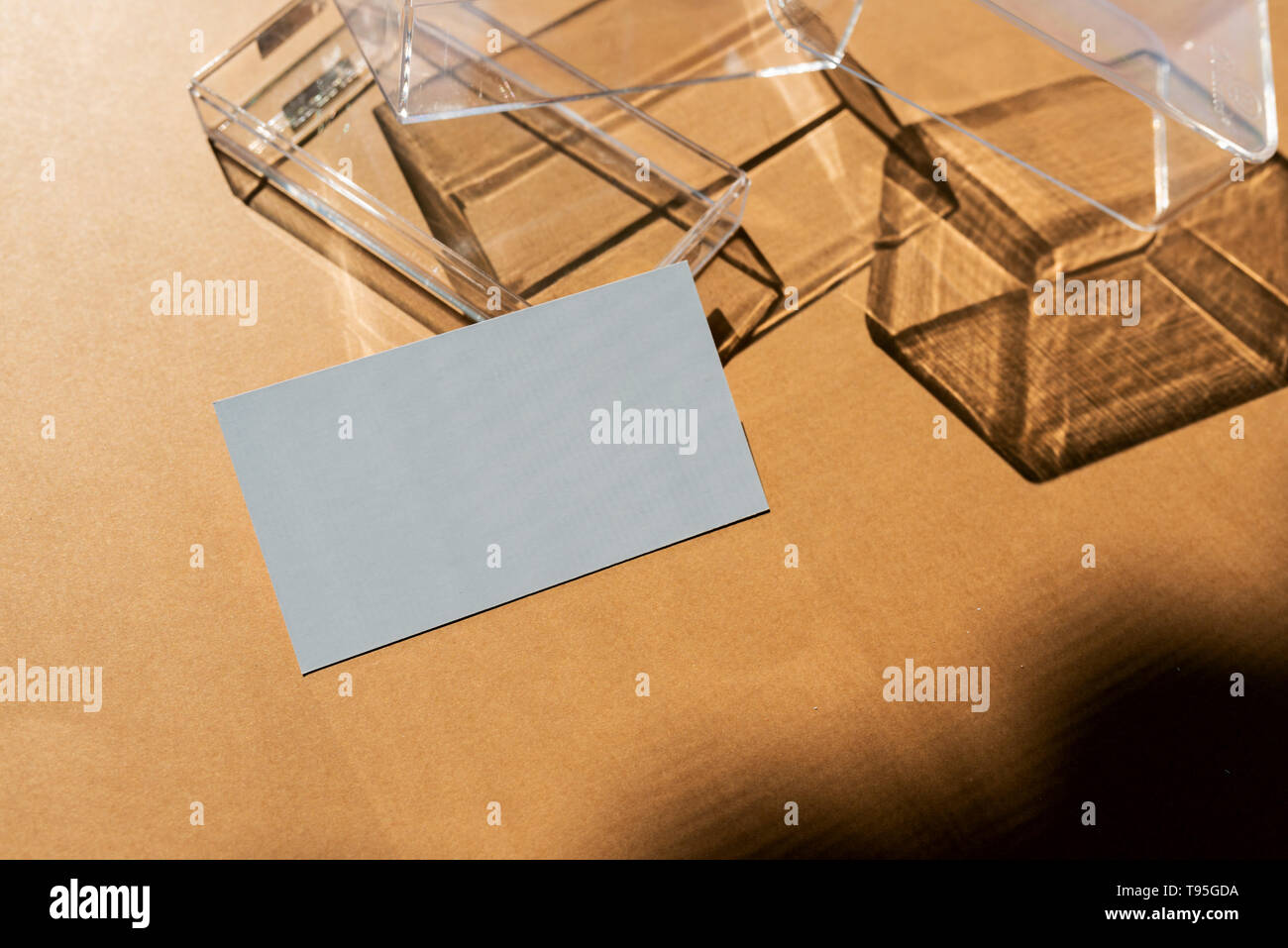 Blank business cards on transparent box, and direct light forming geometric shadows Stock Photo