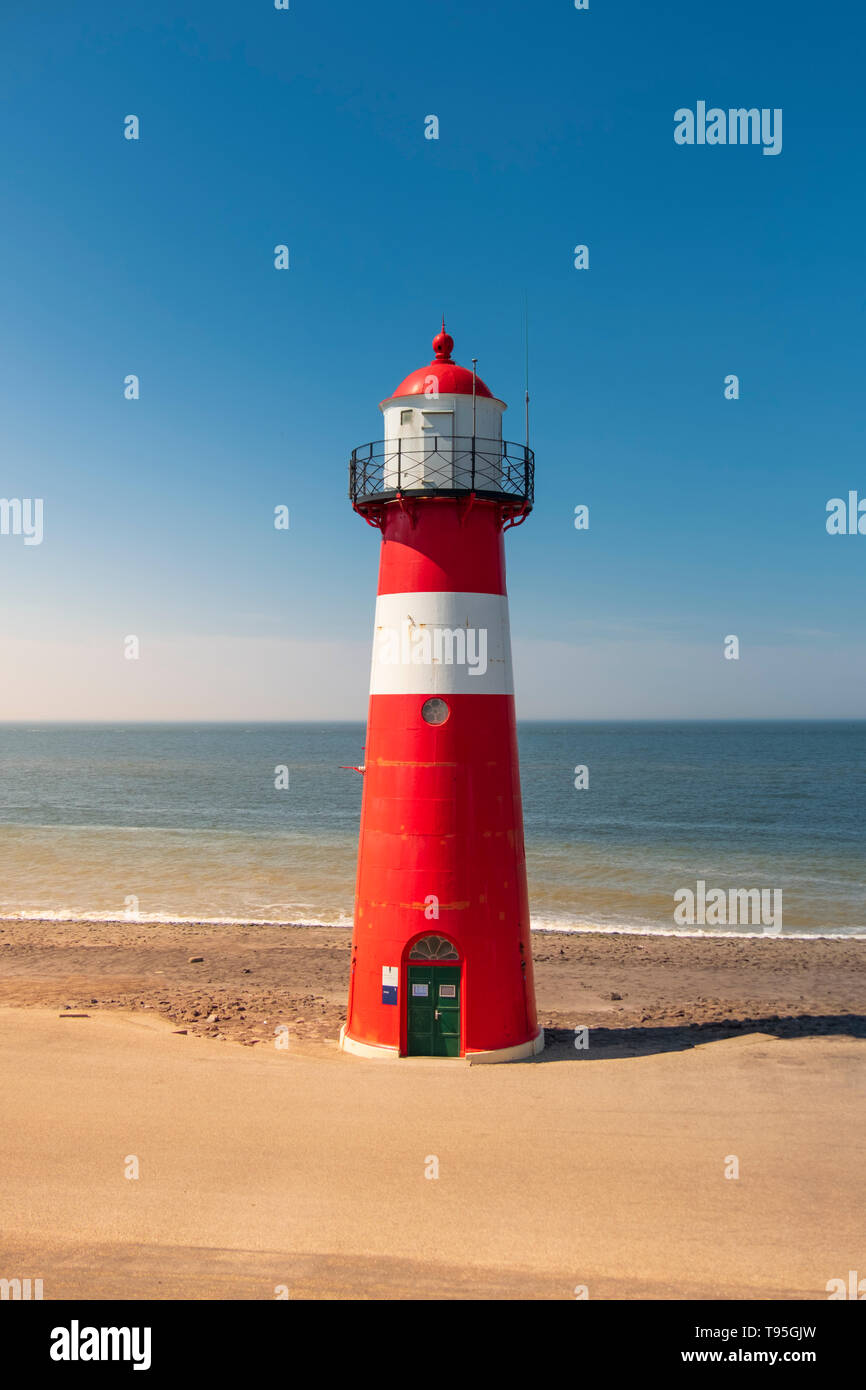 A red and white lighthouse at sea under a clear blue sky near Westkapelle in Zeeland, The Netherlands. Stock Photo