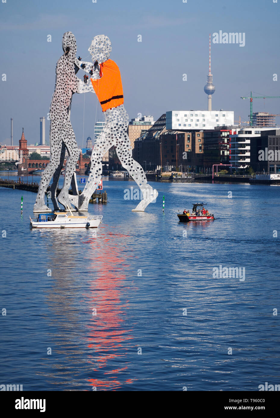 Berlin, Germany. 17th May, 2019. Activists hang from the artwork Molecule Man by US sculptor Jonathan Borofsky in the Spree River and have one of the figures put on an oversized life jacket. They protested against the European refugee policy. Credit: Annette Riedl/dpa-Zentralbild/dpa/Alamy Live News Stock Photo