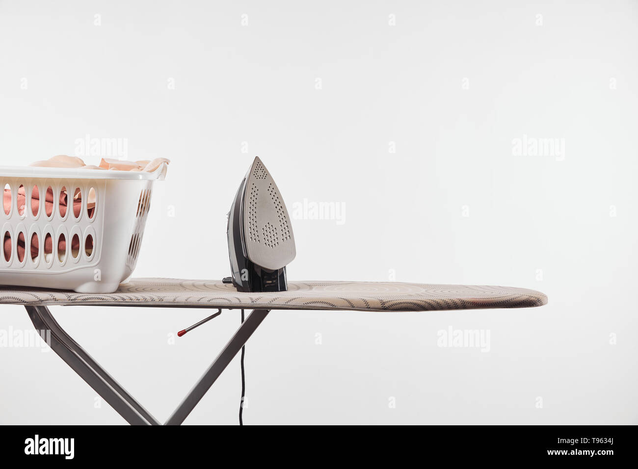 Ironing board, laundry basket and iron isolated on white Stock Photo