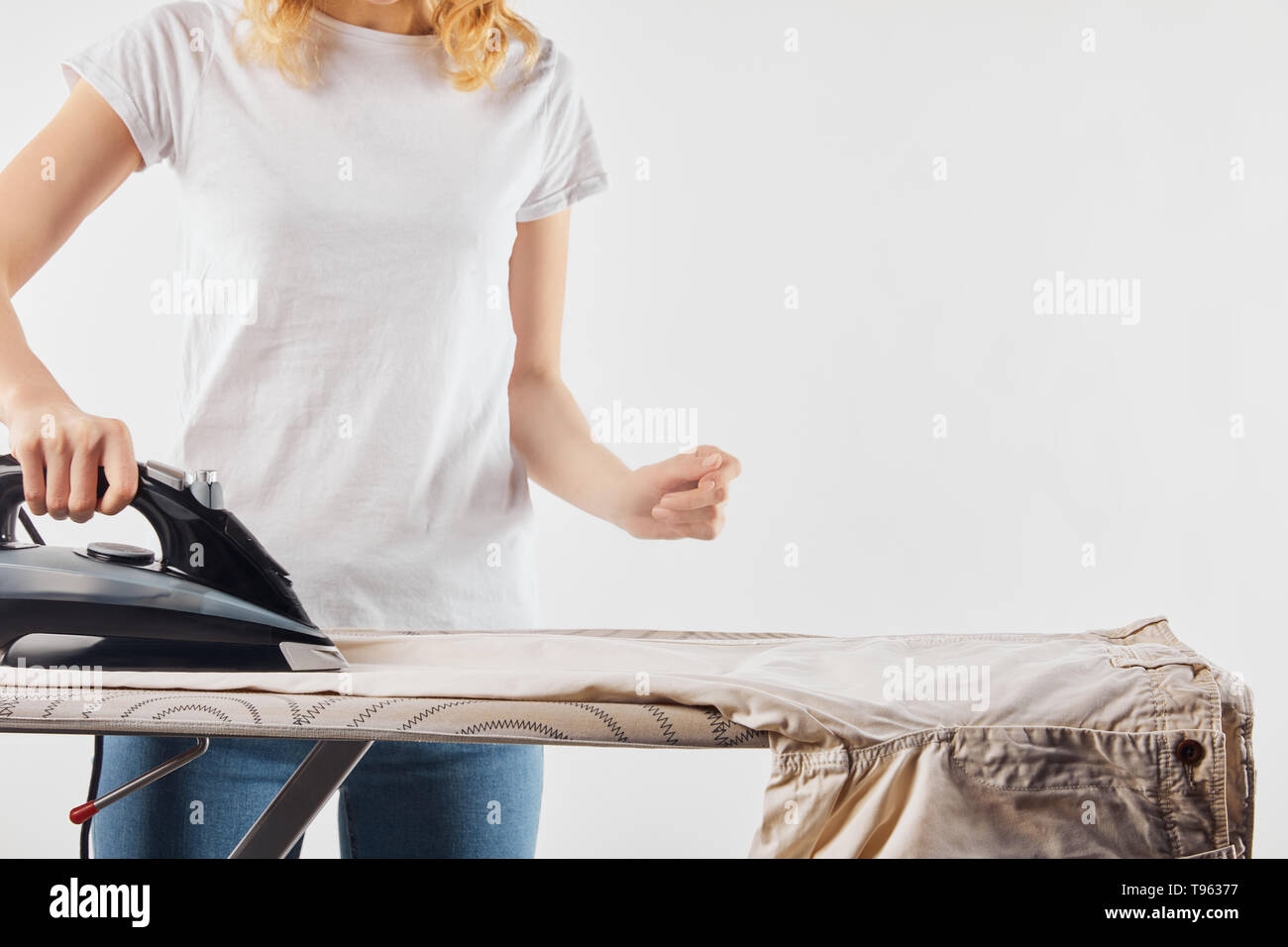 Partial view of woman ironing brown pants isolated on white Stock Photo