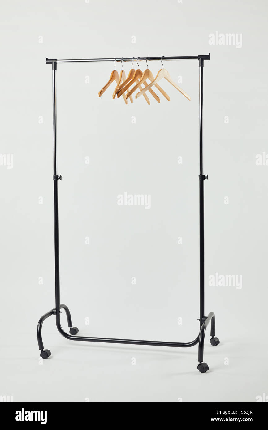 Black steel straight rack with wooden hangers on grey Stock Photo - Alamy