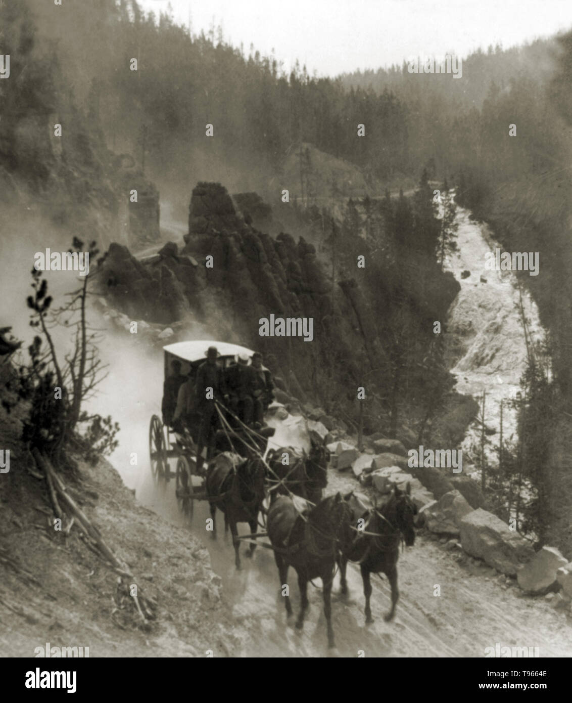 A stagecoach drawn by four horses on the Virginia Canyon Road in Yellowstone National Park, 1905. Virginia Falls is in the background. Stock Photo