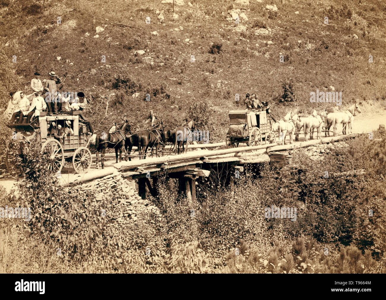 The Deadwood Coach in 1889: two stagecoaches crossing a bridge, with the men waving or tipping their hats to the photographer,  John C. H. Grabill. Deadwood, a city in South Dakota, is a National Historic Landmark District for its well-preserved Gold Rush-era architecture. Stock Photo