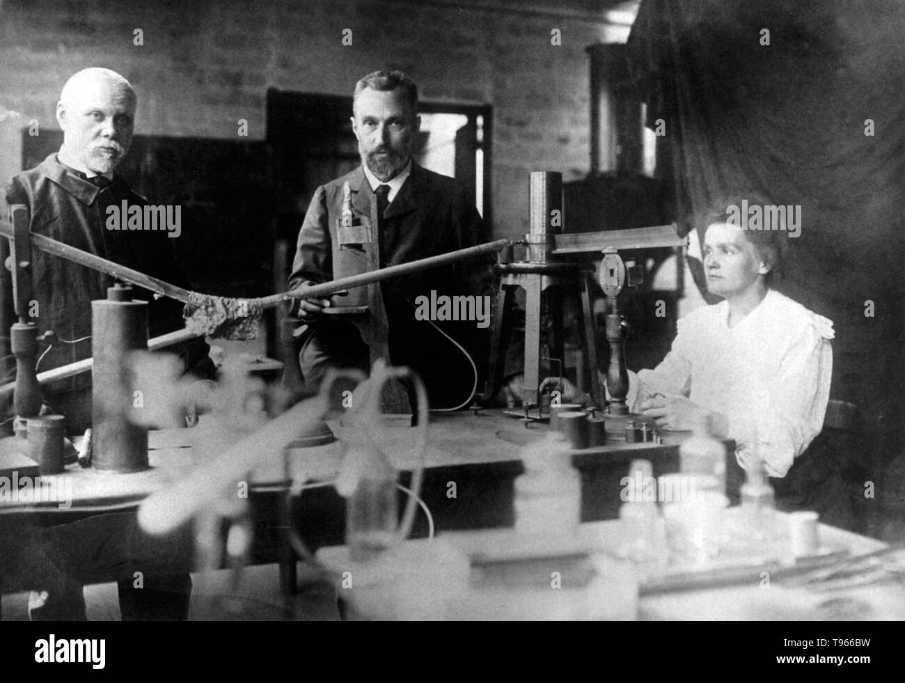Marie and Pierre Curie (center) in their laboratory in Paris with unidentified man. Pierre Curie was introduced to Maria Sklodowska by a friend and took Maria into his laboratory as his student. He began to regard her as his muse. She refused his initial proposal, but finally agreed to marry him on July 26, 1895. Marie Curie (November 7, 1867 - July 4, 1934) was a Polish-French physicist and chemist. Stock Photo