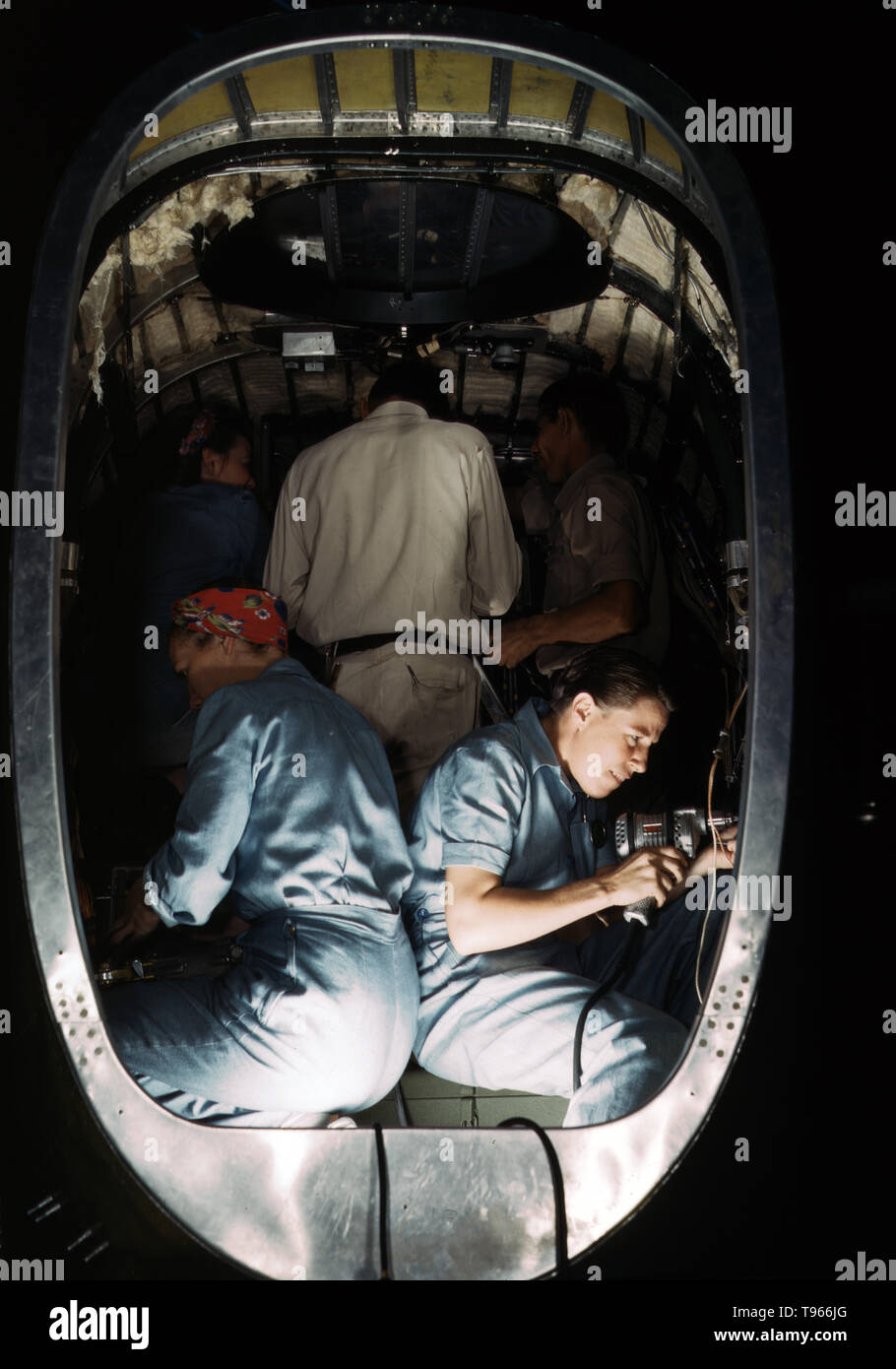 Working inside fuselage of a Liberator Bomber, Consolidated Aircraft Corp., Fort Worth, Texas. Although the image of 'Rosie the Riveter' reflected the industrial work of welders and riveters, the majority of working women filled non-factory positions in every sector of the economy. What unified the experiences of these women was that they proved to themselves, and the country, that they could do a man's job and could do it well. Photographed by Howard R. Hollem, 1942. Stock Photo