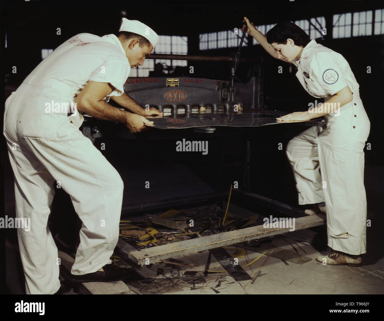 Learning to work a cutting machine, these two NYA employees receive training to fit them for important work, Corpus Christi, Texas. After eight weeks they will be eligible for civil service jobs at the Naval Air Base. Although the image of 'Rosie the Riveter' reflected the industrial work of welders and riveters, the majority of working women filled non-factory positions in every sector of the economy. What unified the experiences of these women was that they proved to themselves, and the country, that they could do a man's job and could do it well. Photographed by Howard R. Hollem, 1942. Stock Photo