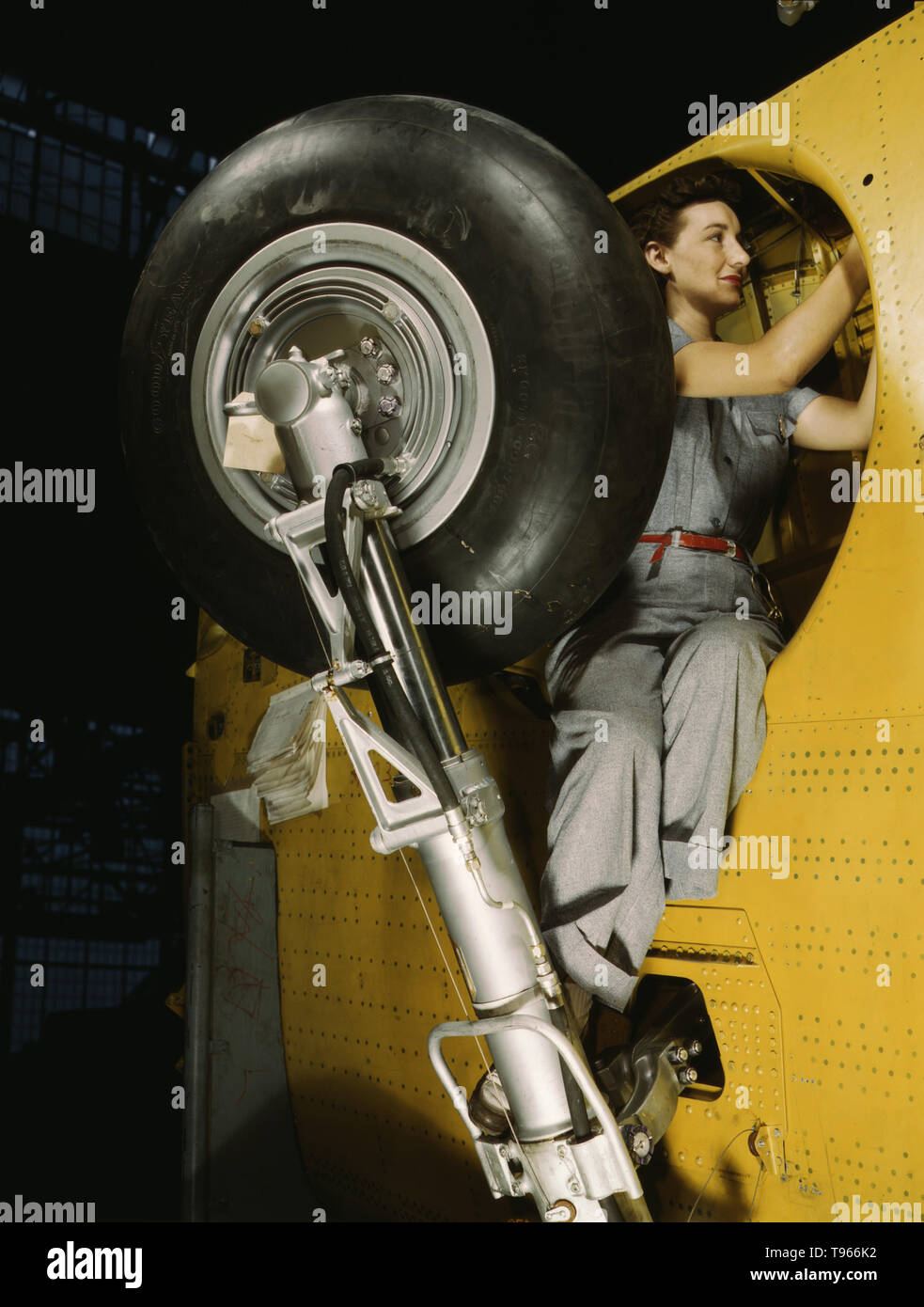 This woman worker at the Vultee-Nashville is shown making final adjustments in the wheel well of an inner wing before the installation of the landing gear, Nashville, Tenn. This is one of the numerous assembly operations in connection with the mass production of Vultee Vengeance dive bombers. Although the image of 'Rosie the Riveter' reflected the industrial work of welders and riveters, the majority of working women filled non-factory positions in every sector of the economy. Stock Photo