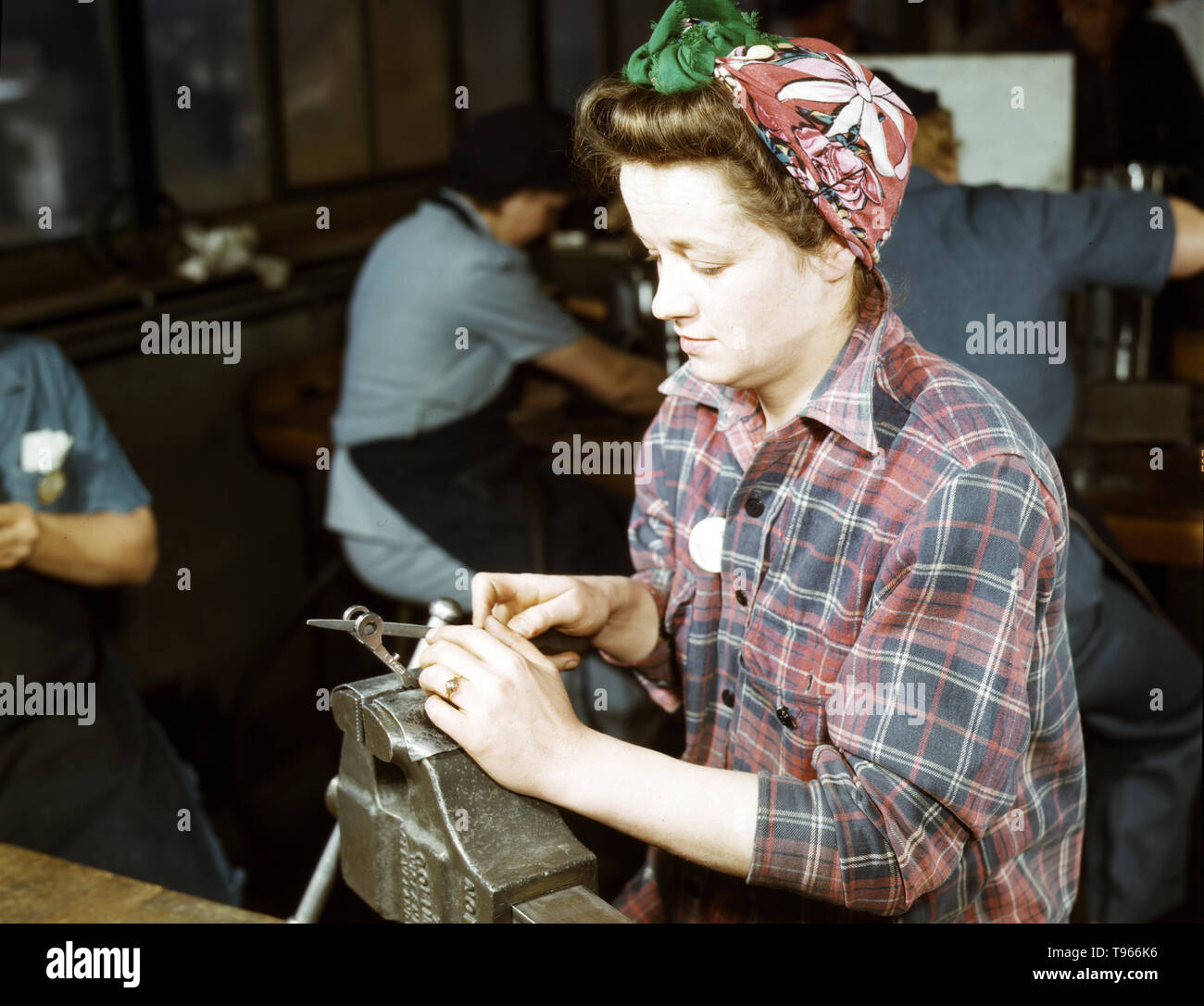 One of the girls of Vilter Manufacturing Company filing small gun parts, Milwaukee, Wisconsin. One brother in Coast Guard, one going to Army. Although the image of 'Rosie the Riveter' reflected the industrial work of welders and riveters, the majority of working women filled non-factory positions in every sector of the economy. What unified the experiences of these women was that they proved to themselves, and the country, that they could do a man's job and could do it well. Photographed by Howard R. Hollem, 1943. Stock Photo