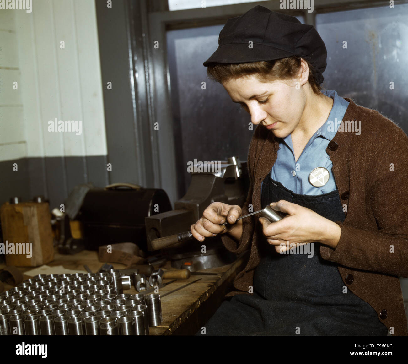War production workers at the Vilter Manufacturing Company making M5 and M7 guns for the U.S. Army, Milwaukee, Wisconsin. Ex-housewife, age 24, filing small parts. Her husband and brother are in the armed service. Although the image of 'Rosie the Riveter' reflected the industrial work of welders and riveters, the majority of working women filled non-factory positions in every sector of the economy. What unified the experiences of these women was that they proved to themselves, and the country, that they could do a man's job and could do it well. Photographed by Howard R. Hollem, 1943. Stock Photo