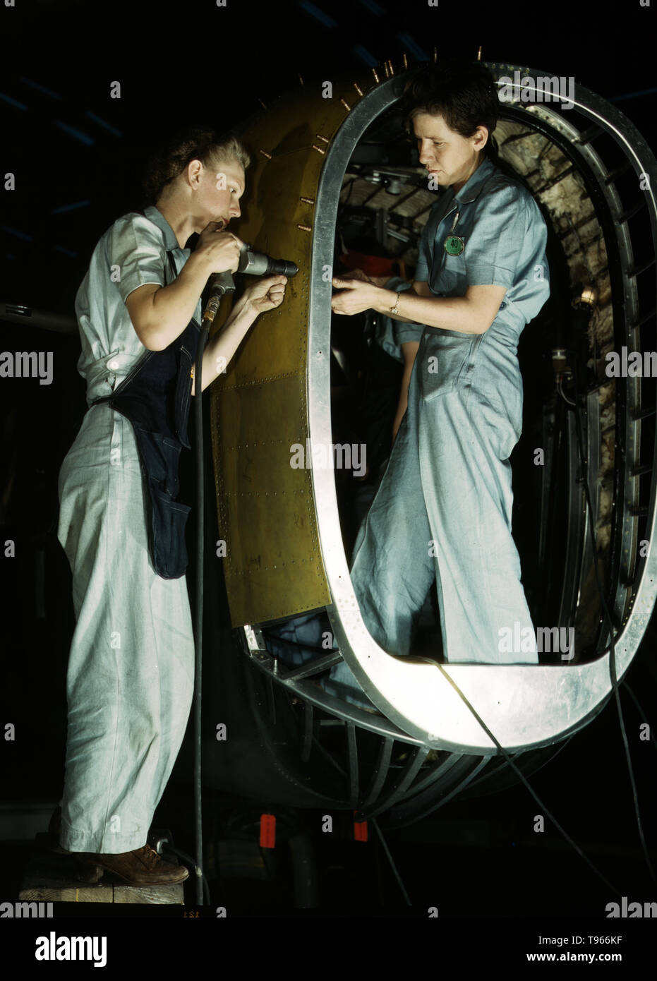 Frances Eggleston, aged 23, came from Oklahoma, used to do office work. Removing paper from pilot's window(?), Consolidated Aircraft Corp., Fort Worth, Texas. Although the image of "Rosie the Riveter" reflected the industrial work of welders and riveters, the majority of working women filled non-factory positions in every sector of the economy. What unified the experiences of these women was that they proved to themselves, and the country, that they could do a man's job and could do it well. Photographed by Howard R. Hollem, 1942. Stock Photo