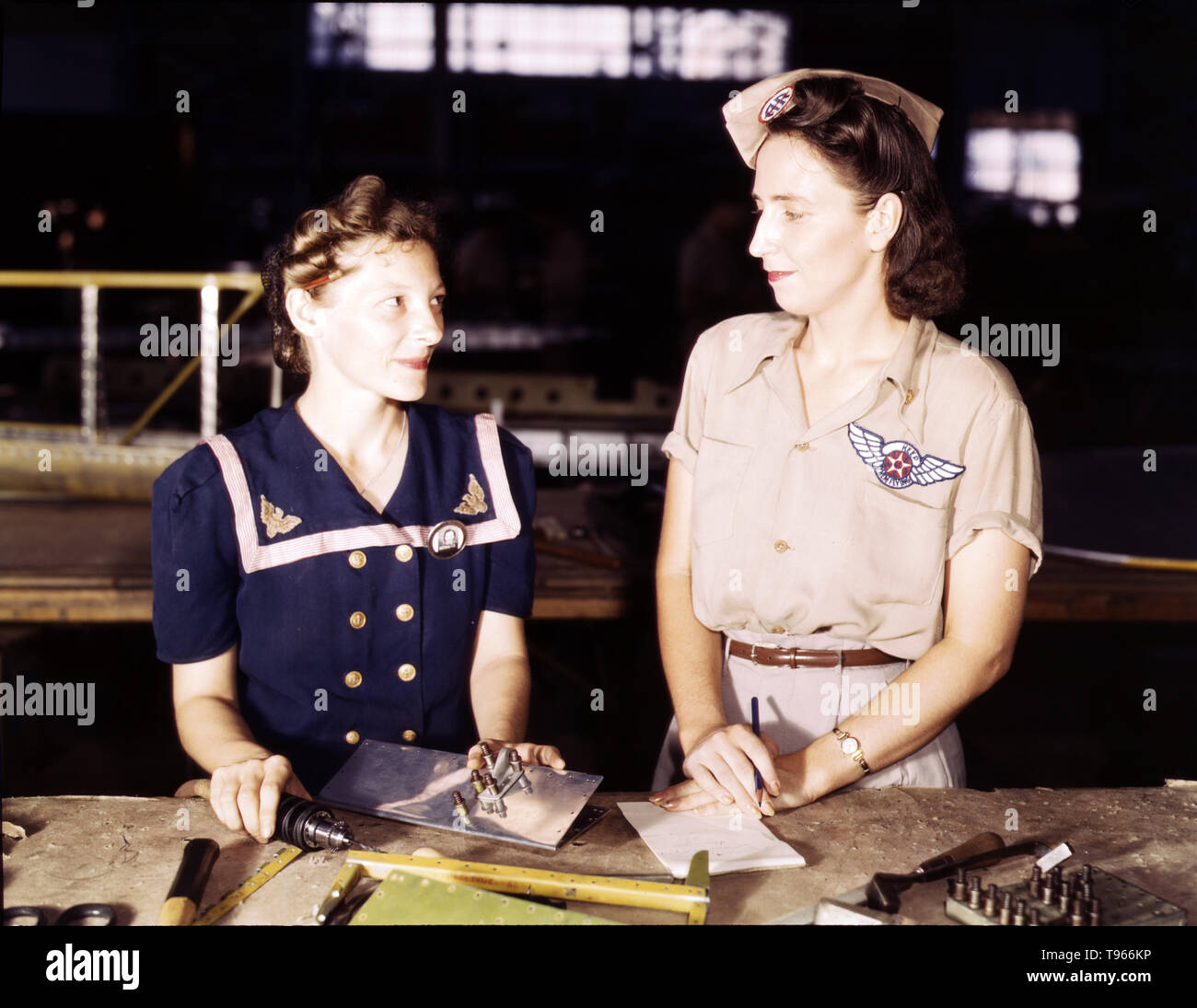 Pearl Harbor widows have gone into war work to carry on the fight with a personal vengeance, Corpus Christi, Texas. Mrs. Virginia Young (right) whose husband was one of the first casualties of WWII, is a supervisor in the Assembly and Repairs Department of the Naval Air Base. Her job is to find convenient and comfortable living quarters for women workers from out of the state, like Ethel Mann, who operates an electric drill.  Photographed by Howard R. Hollem, 1942. Stock Photo