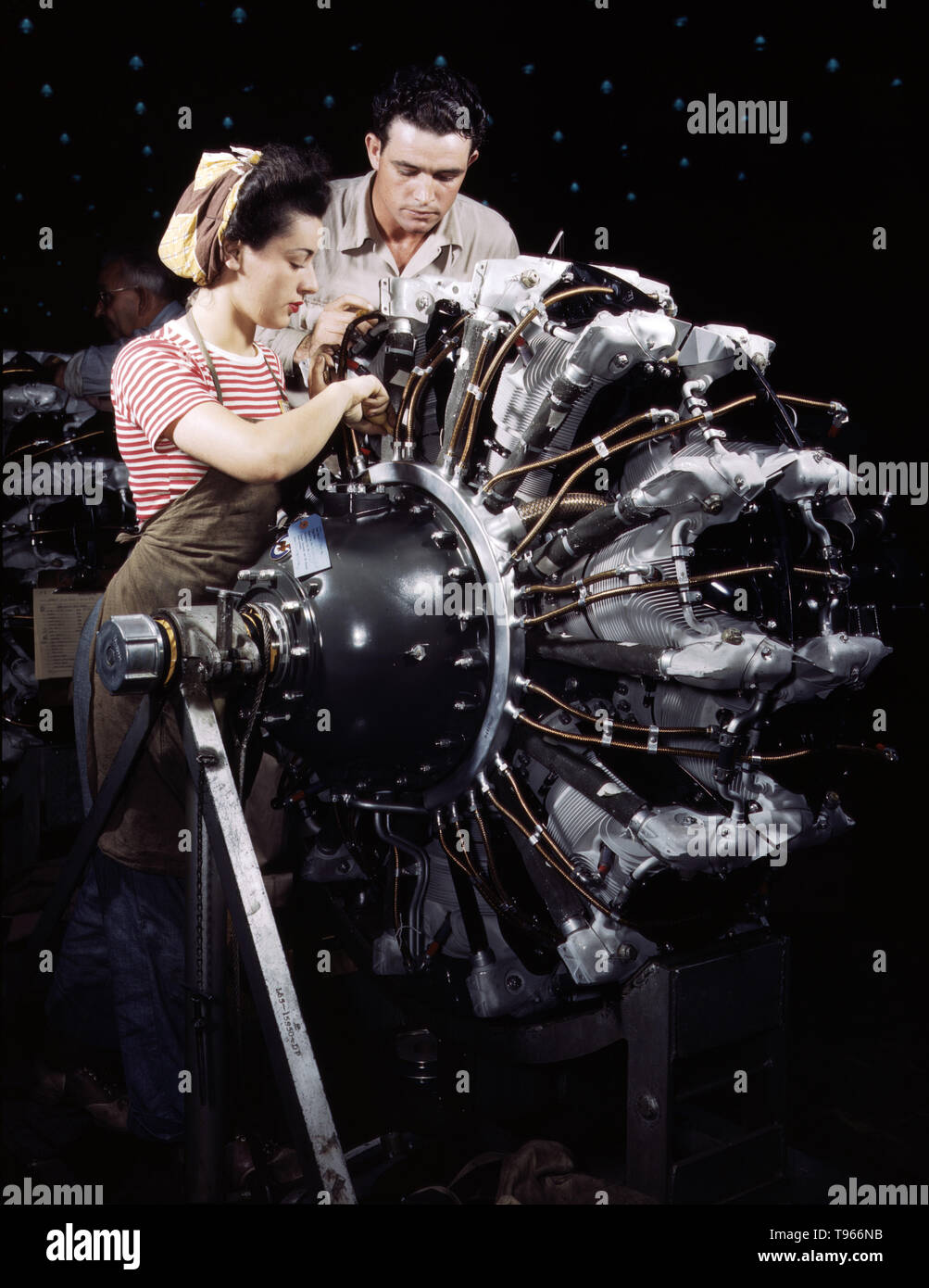 Women are trained as engine mechanics in thorough Douglas training methods, Douglas Aircraft Company, Long Beach, California. Although the image of 'Rosie the Riveter' reflected the industrial work of welders and riveters, the majority of working women filled non-factory positions in every sector of the economy. What unified the experiences of these women was that they proved to themselves, and the country, that they could do a man's job and could do it well. Photographed by Alfred T. Palmer, 1942. Stock Photo