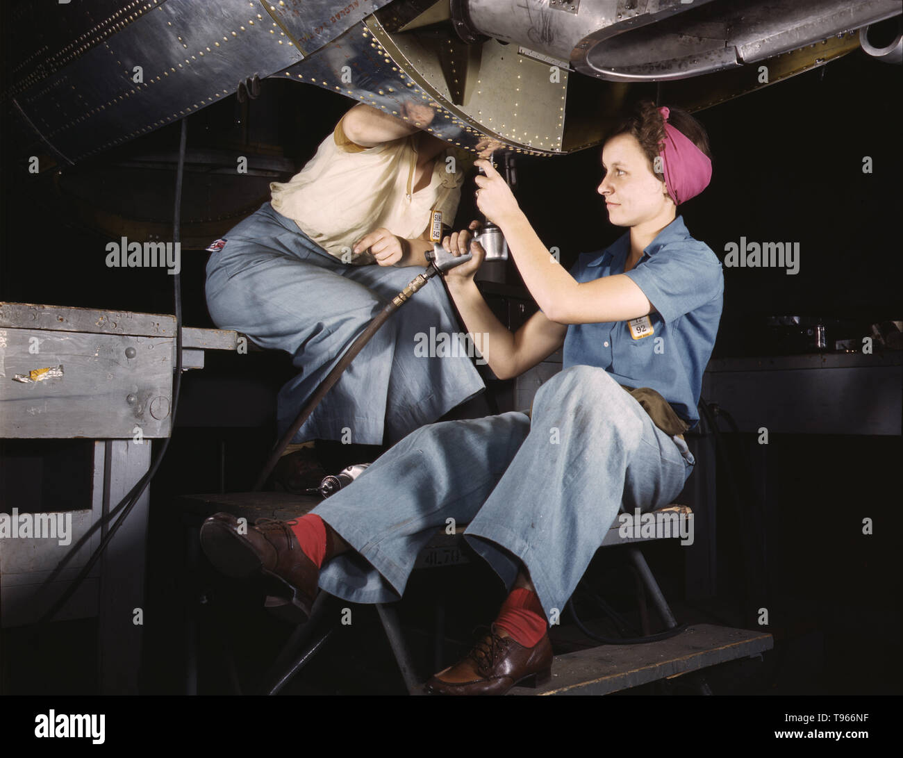Women at work on bomber, Douglas Aircraft Company, Long Beach, California. Although the image of 'Rosie the Riveter' reflected the industrial work of welders and riveters, the majority of working women filled non-factory positions in every sector of the economy. What unified the experiences of these women was that they proved to themselves, and the country, that they could do a man's job and could do it well. Photographed by Alfred T. Palmer, 1942. Stock Photo
