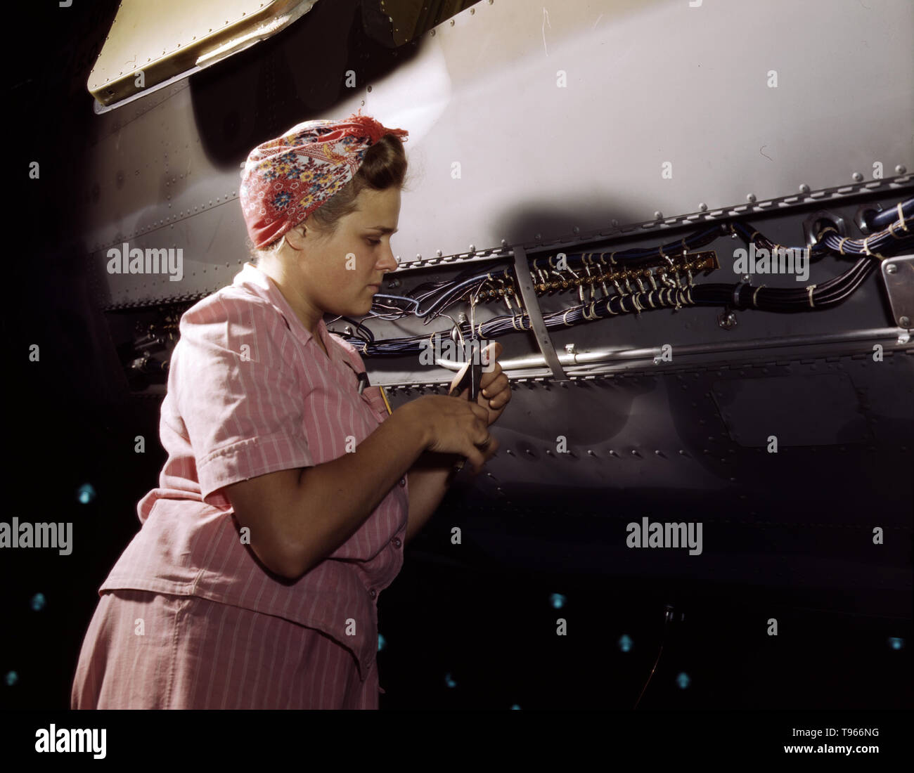 With careful Douglas training, women do accurate electrical assembly and installation work, Douglas Aircraft Company, Long Beach, California. Although the image of 'Rosie the Riveter' reflected the industrial work of welders and riveters, the majority of working women filled non-factory positions in every sector of the economy. What unified the experiences of these women was that they proved to themselves, and the country, that they could do a man's job and could do it well. Photographed by Alfred T. Palmer, 1942. Stock Photo