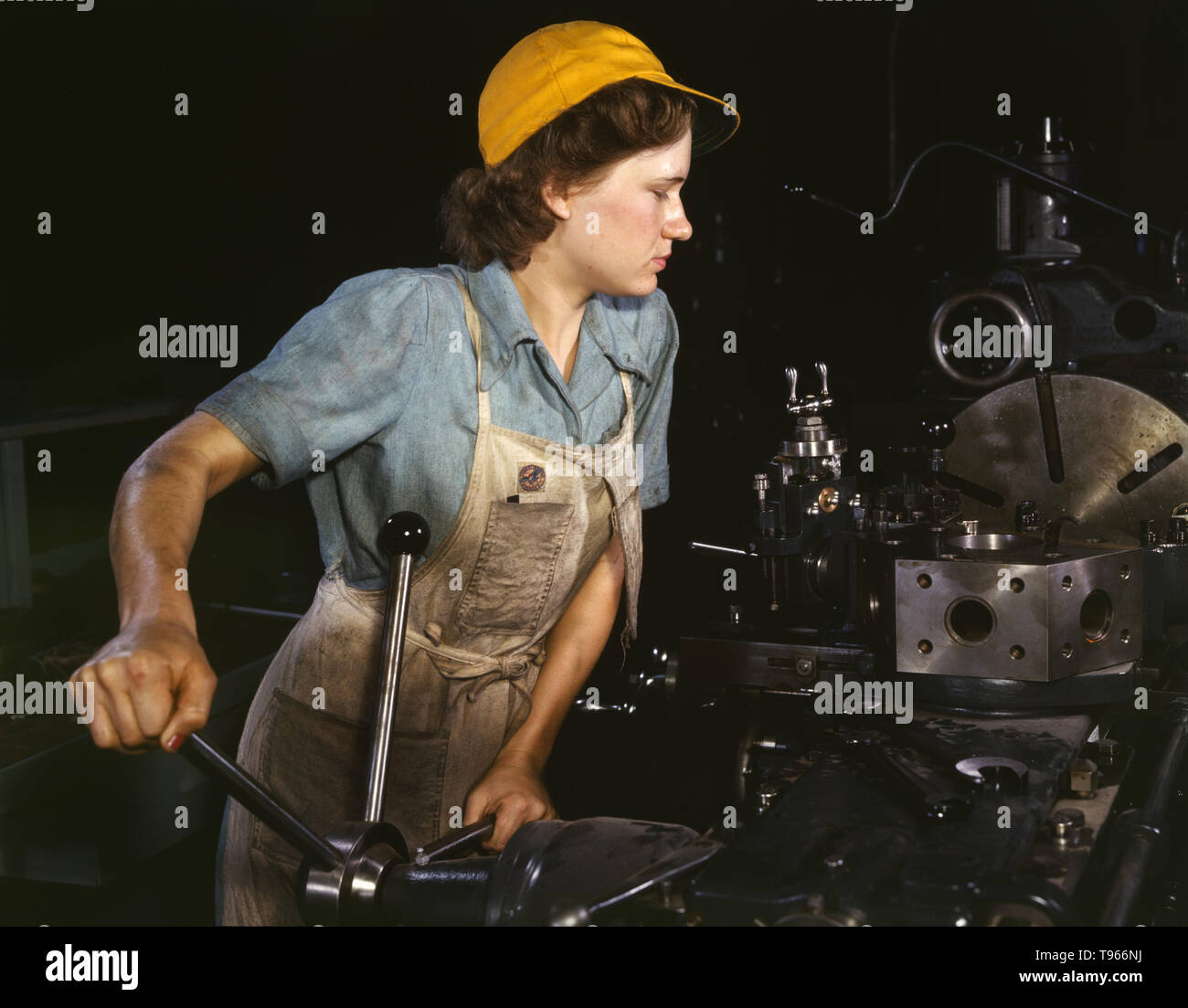Lathe operator machining parts for transport planes at the Consolidated Aircraft Corporation plant, Fort Worth, Texas. Although the image of 'Rosie the Riveter' reflected the industrial work of welders and riveters, the majority of working women filled non-factory positions in every sector of the economy. What unified the experiences of these women was that they proved to themselves, and the country, that they could do a man's job and could do it well. Photographed by Howard R. Hollem, 1942. Stock Photo
