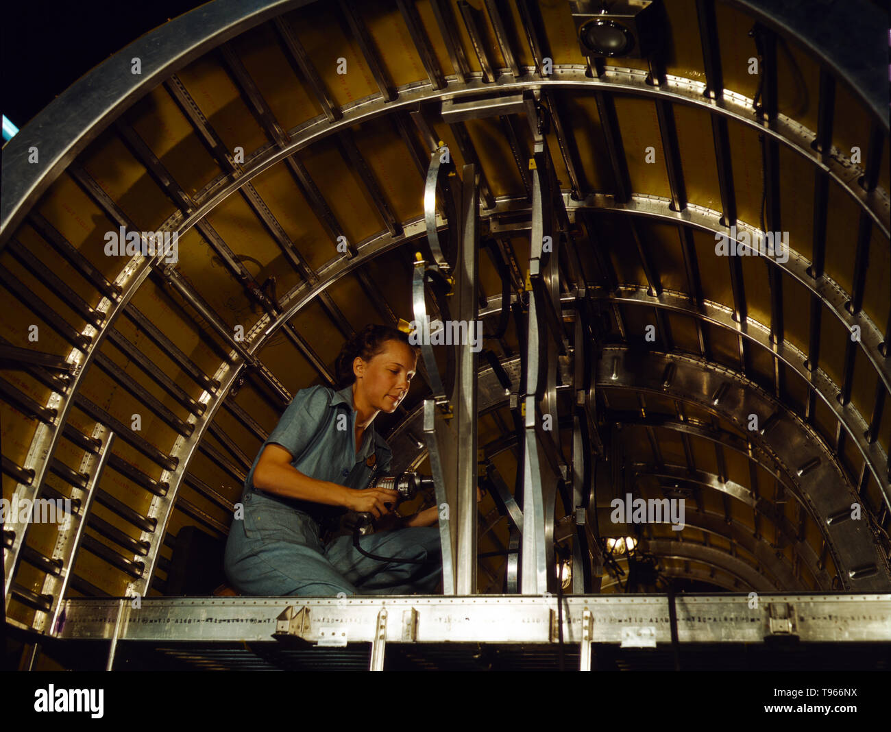 Production of B-24 bombers and C-87 transports, Consolidated Aircraft Corp., Fort Worth, Texas. Cabbie Coleman, former housewife, works at western aircraft plant. Installing of oxygen racks above the flight deck. Although the image of 'Rosie the Riveter' reflected the industrial work of welders and riveters, the majority of working women filled non-factory positions in every sector of the economy. What unified the experiences of these women was that they proved to themselves, and the country, that they could do a man's job and could do it well. Photographed by Howard R. Hollem, 1942. Stock Photo