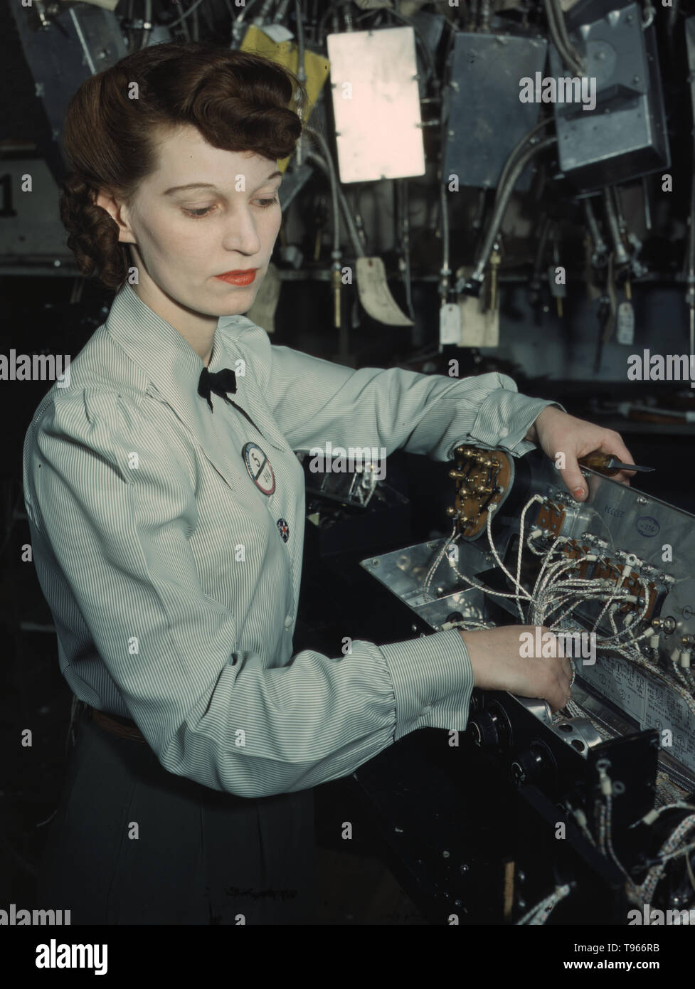 Electronics technician, Goodyear Aircraft Corp., Akron, Ohio. Although the image of 'Rosie the Riveter' reflected the industrial work of welders and riveters, the majority of working women filled non-factory positions in every sector of the economy. What unified the experiences of these women was that they proved to themselves, and the country, that they could do a man's job and could do it well. Photographed by Alfred T. Palmer, 1941. Stock Photo