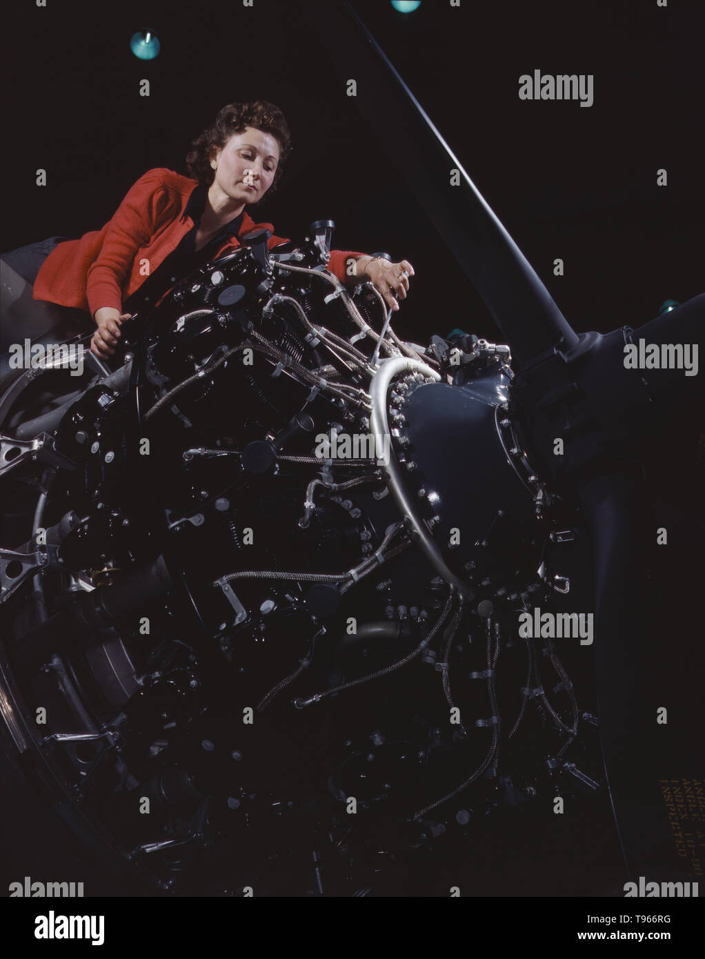 Woman at work on motor, Douglas Aircraft Company, Long Beach, California. Although the image of 'Rosie the Riveter' reflected the industrial work of welders and riveters, the majority of working women filled non-factory positions in every sector of the economy. What unified the experiences of these women was that they proved to themselves, and the country, that they could do a man's job and could do it well. Photographed by Alfred T. Palmer, 1942. Stock Photo