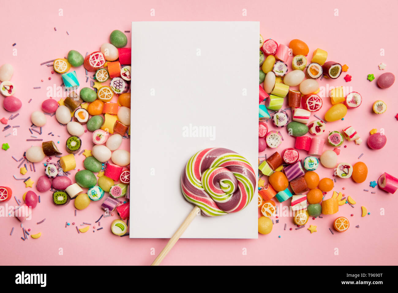 top view of delicious candies, lollipop and white card with copy space on pink background Stock Photo