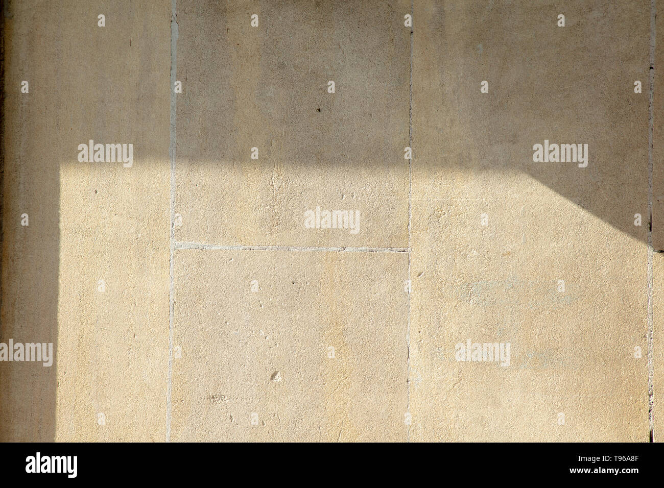 Plane and almost three dimensional surface with shadows of the creamy coloured natural Portland stone from the quarries of the Isle of Portland, UK. Stock Photo