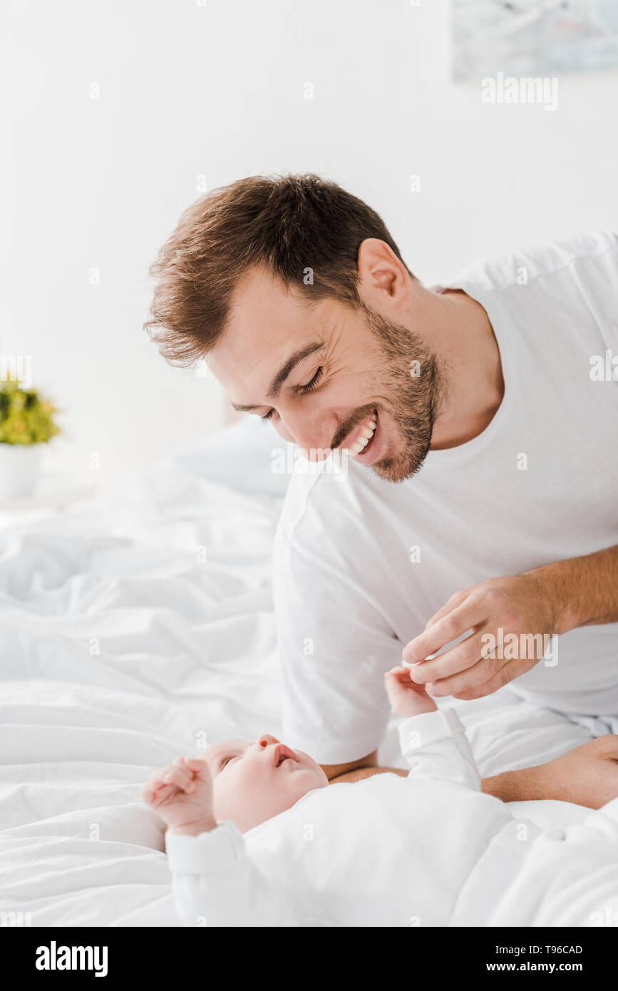 Happy young father lying on bed with baby Stock Photo - Alamy