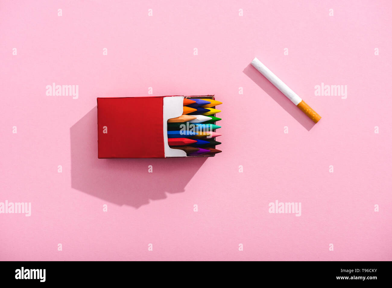 top view of colorful crayons in cigarette pack and tobacco cigarette on