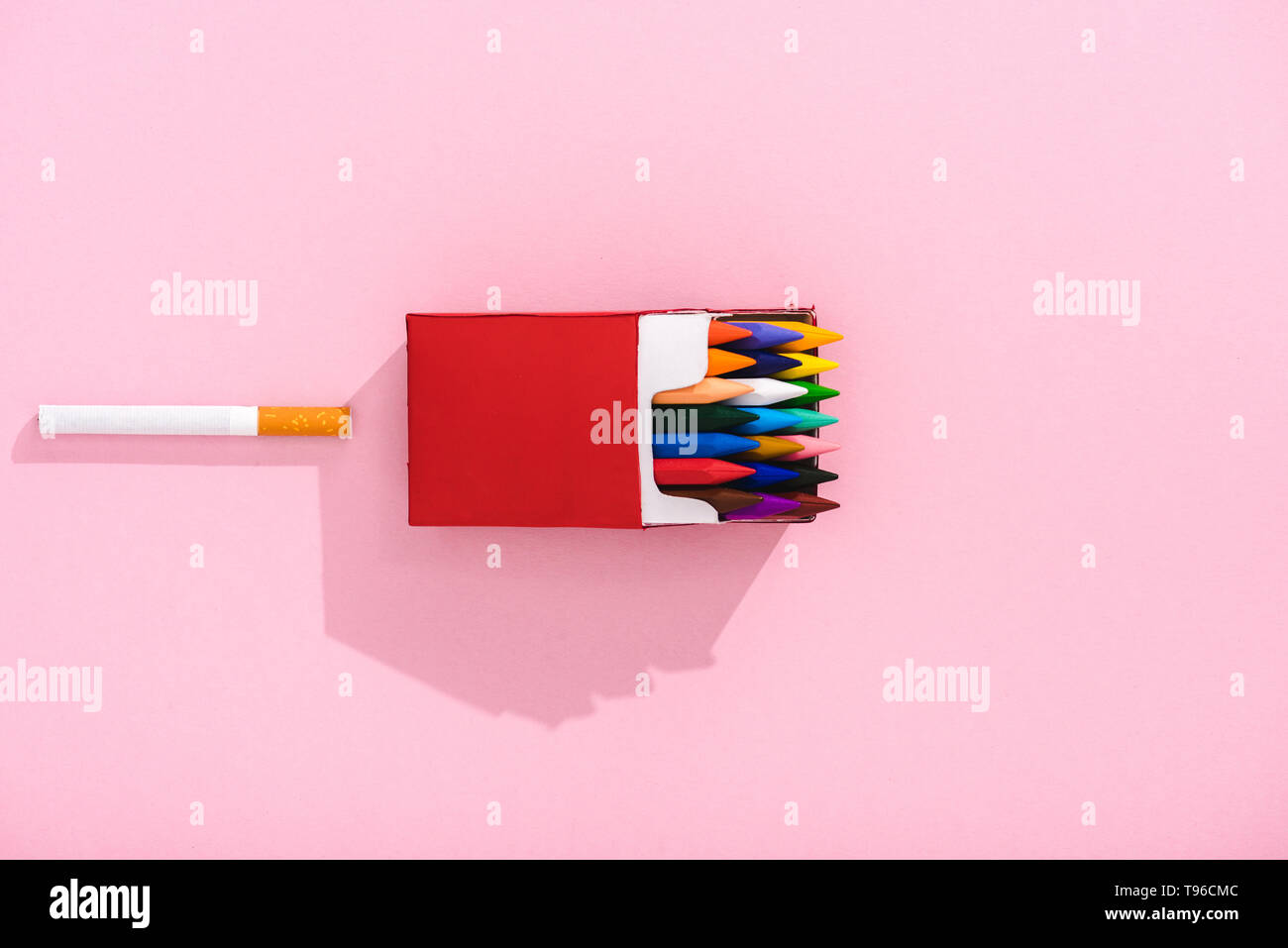 top view of colorful crayons in cigarette pack and tobacco cigarette on