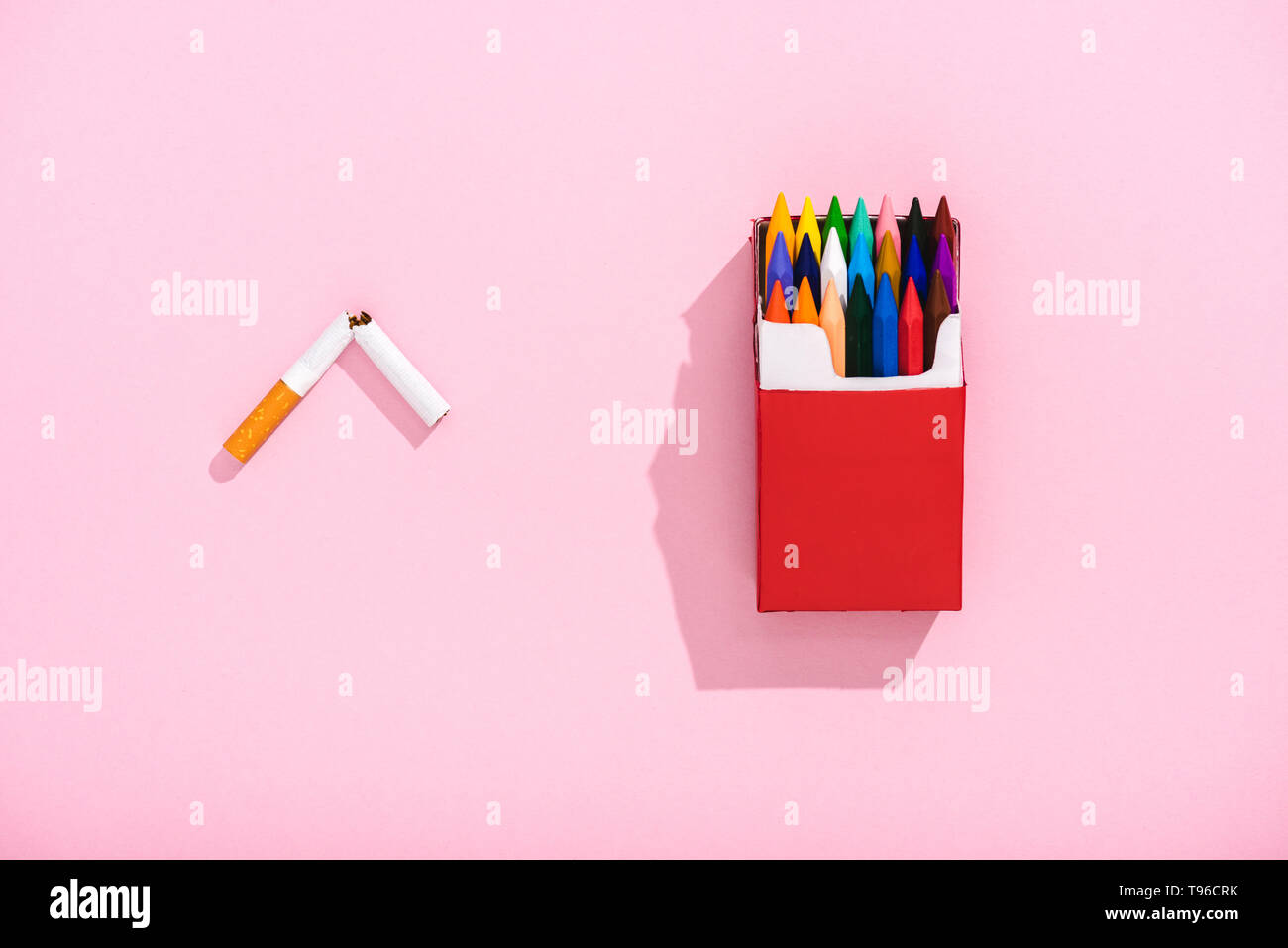 top view of colorful crayons in cigarette pack and broken tobacco cigarette  on pink, smoking concept Stock Photo