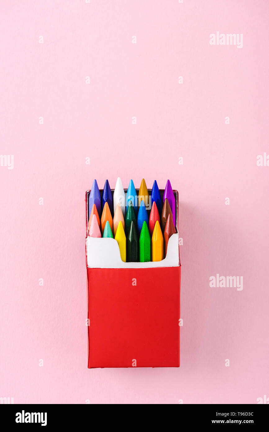 top view of multicolored crayons in red cigarette pack on pink with copy  space, smoking concept Stock Photo