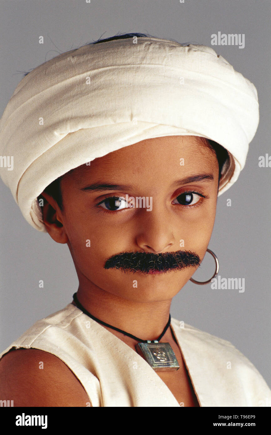 Yound Gujarati boy dressed as an adult famer wearing a traditional outfit with a false moustache, Stock Photo