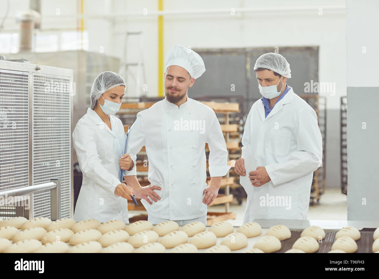 Technologist and baker inspect the bread production line at the bakery ...