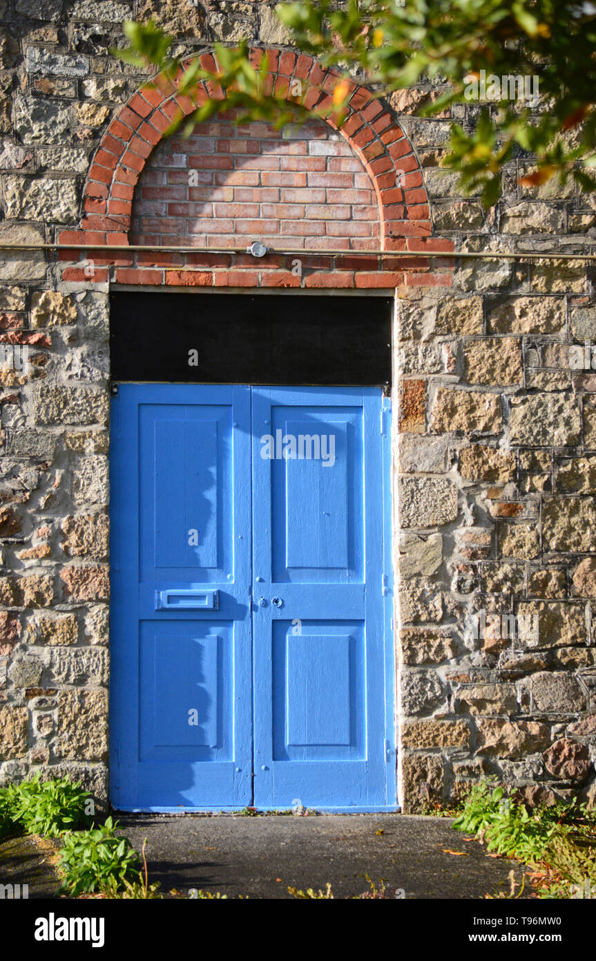 Blue Door set in old stone wall with red brick arch, Ivybridge paper Mill, Devon, England Stock Photo
