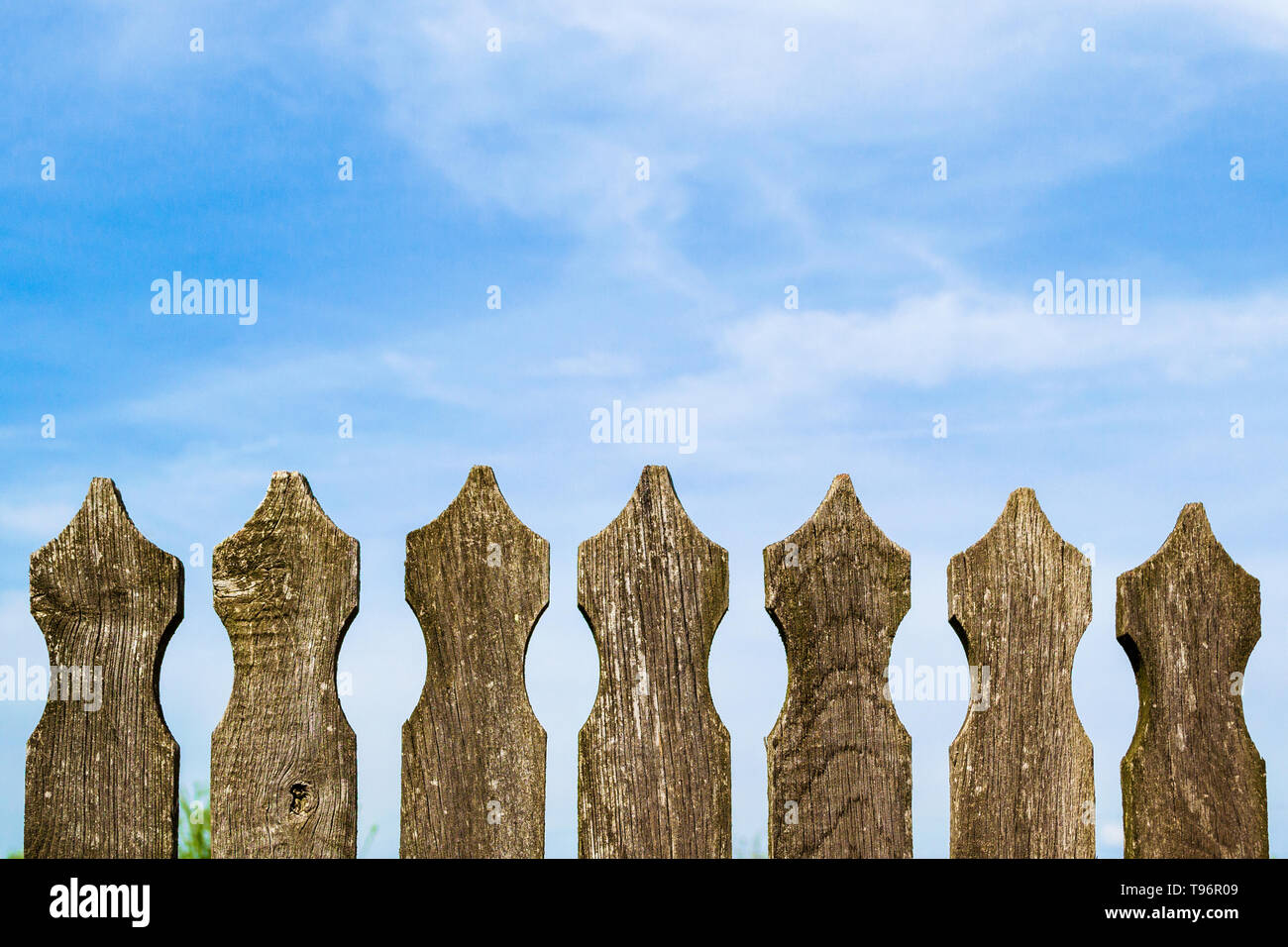 Wooden picket fence on sunny blue sky with dispersing clouds on a ...