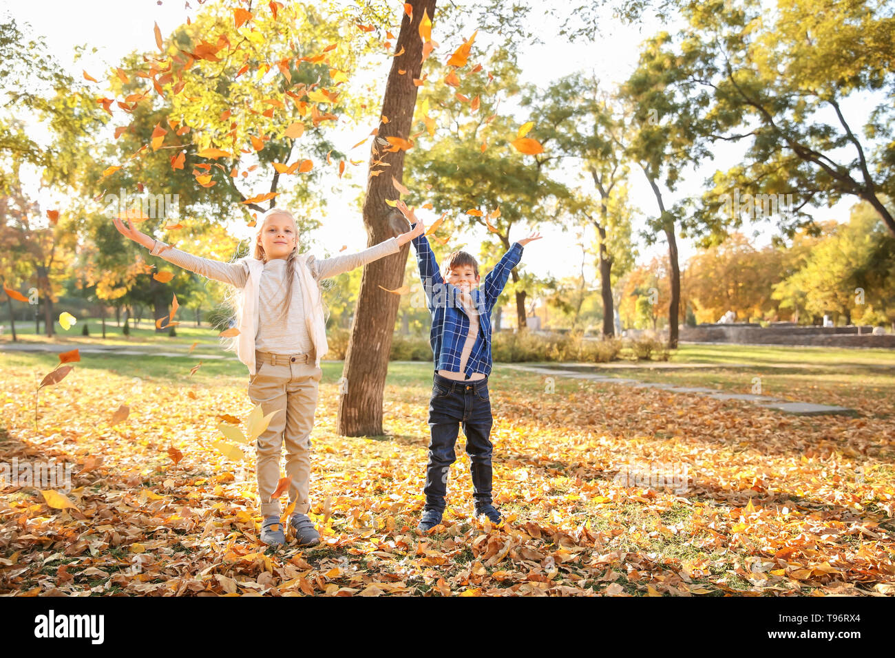 Children playing with leaves in autumn park Stock Photo