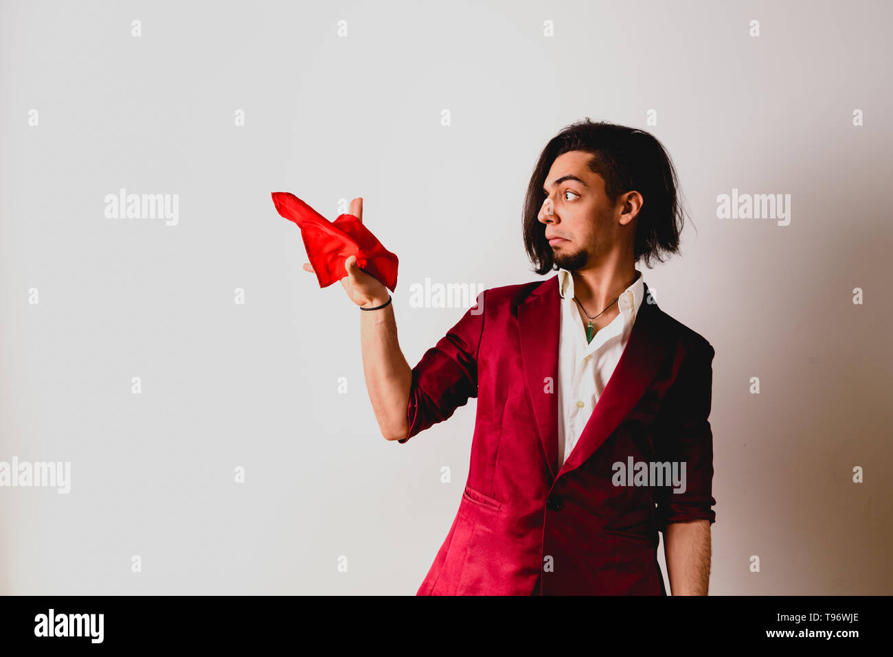 Portrait of young magician handling ropes and bandanas to do magic tricks, isolated on white. Stock Photo