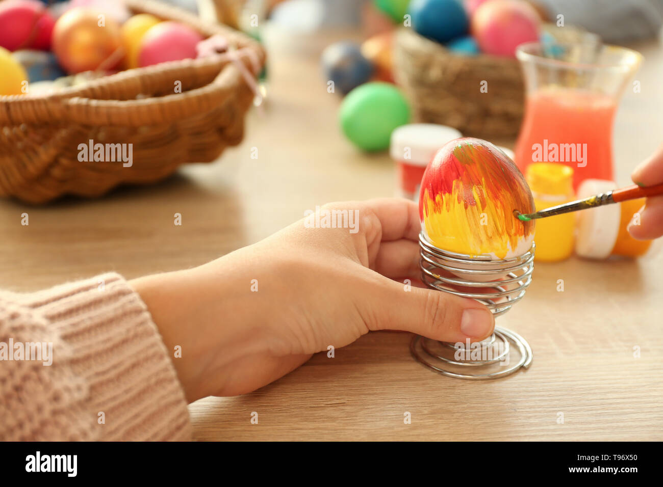 Woman painting Easter eggs on table Stock Photo