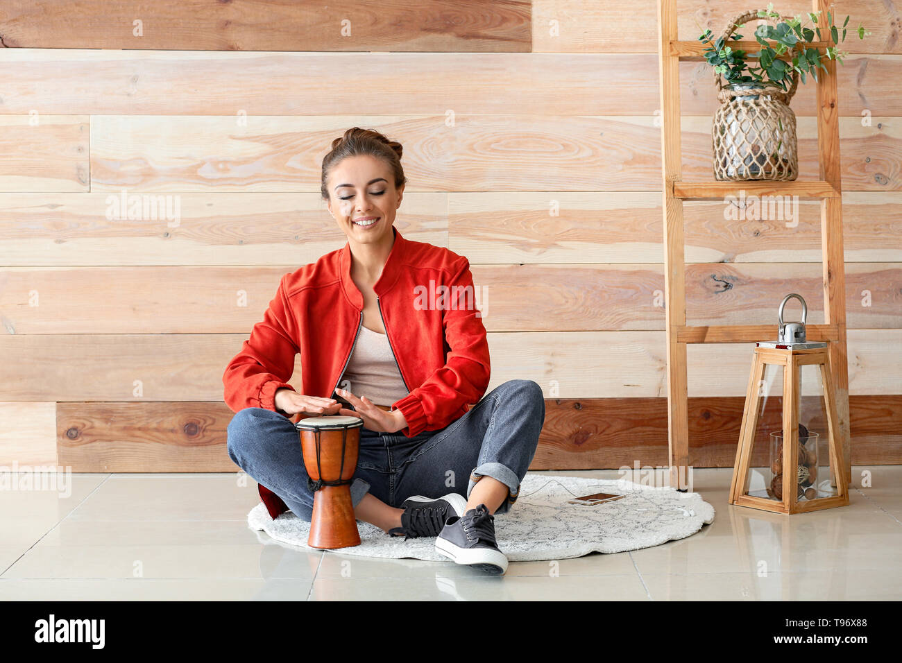 Beautiful woman playing tam-tam near wooden wall Stock Photo