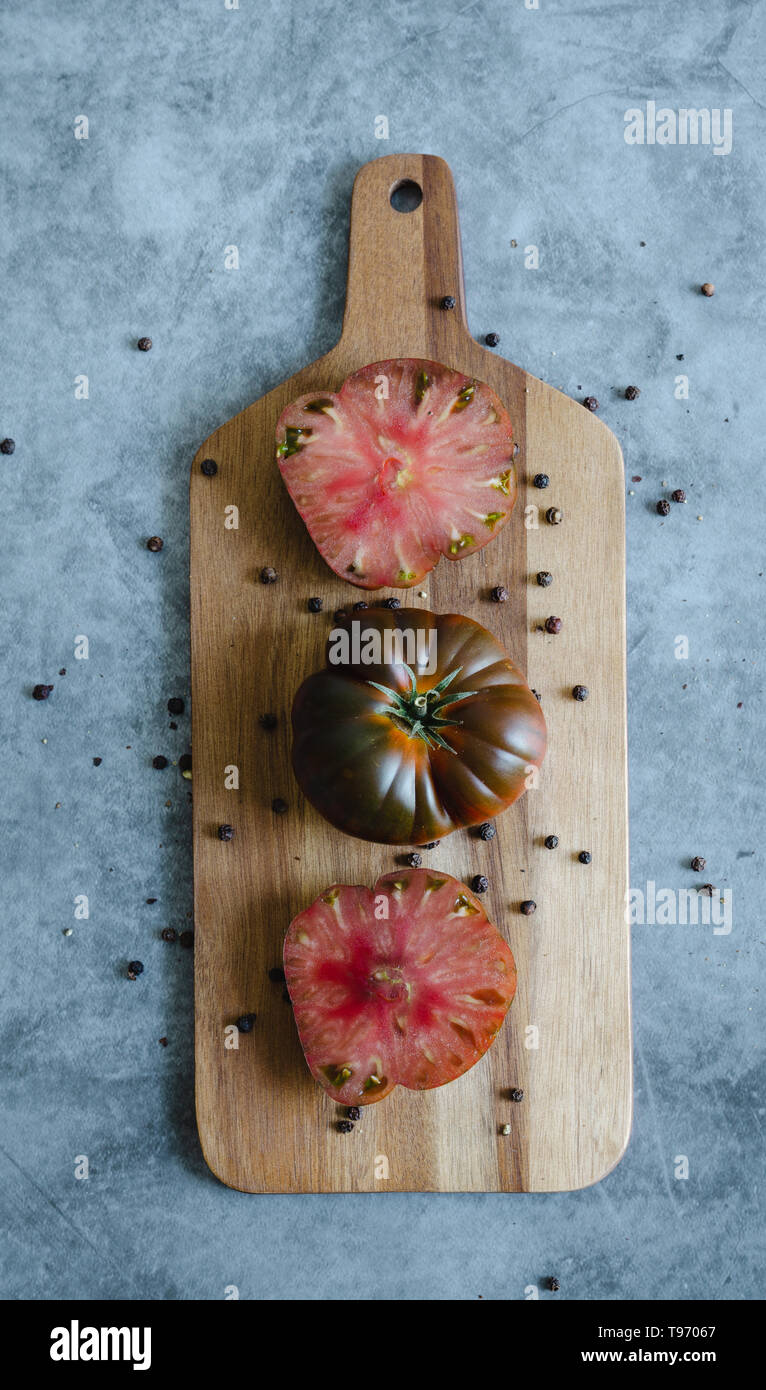 Sweet Marmande tomatoes cut and whole on wooden board. Top view. Stock Photo