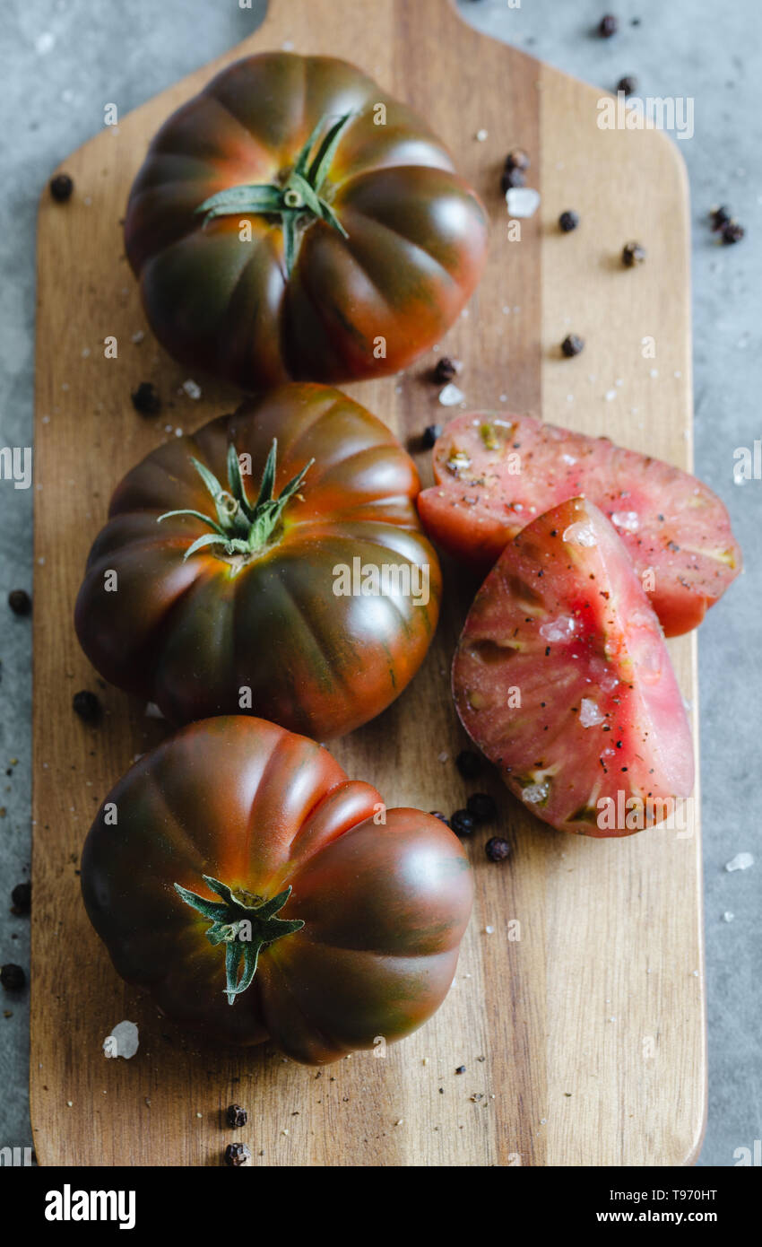 Sweet Marmande tomatoes cut and whole on wooden board. Close view Stock Photo