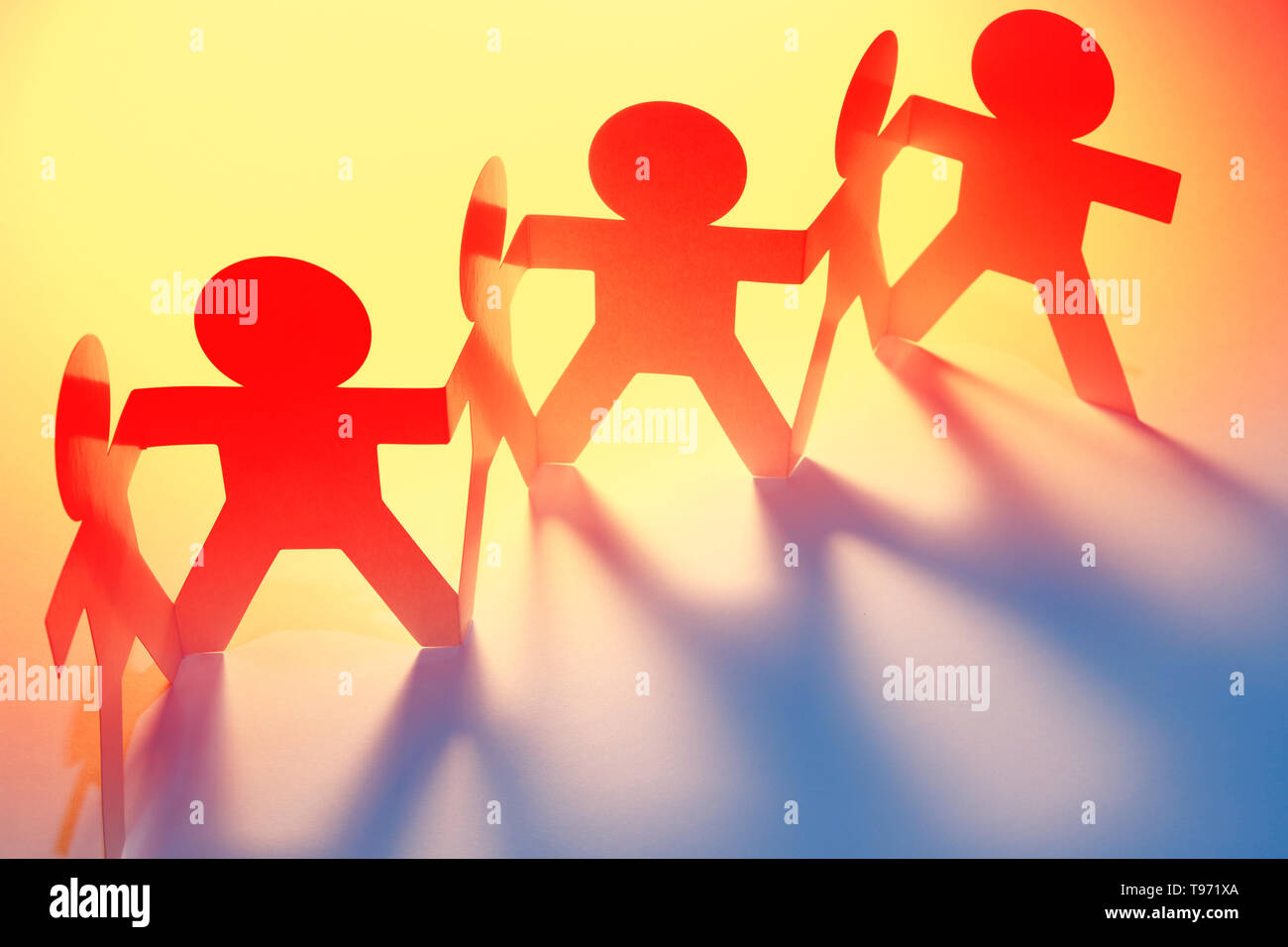 Team of paper chain people in a row holding hands. Copy space Stock ...