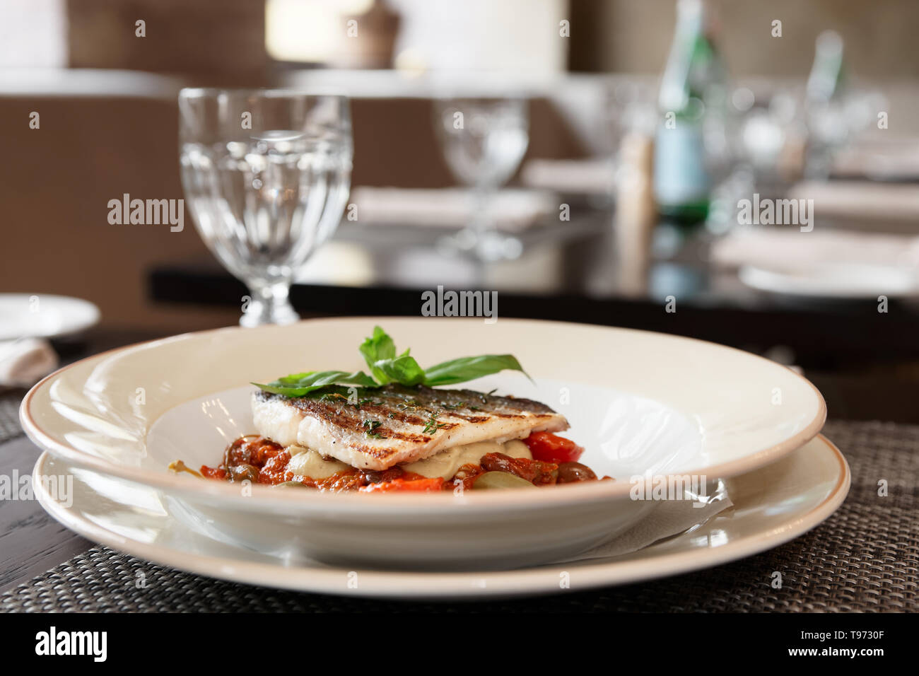 Sea bass fillet with tomato sauce and capers, place setting of a restaurant Stock Photo