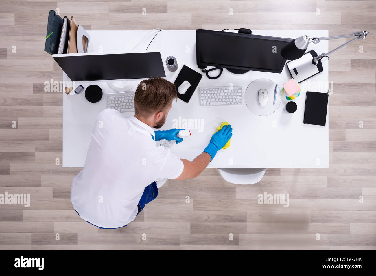 Janitor cleaning white desk in modern office Stock Photo Alamy