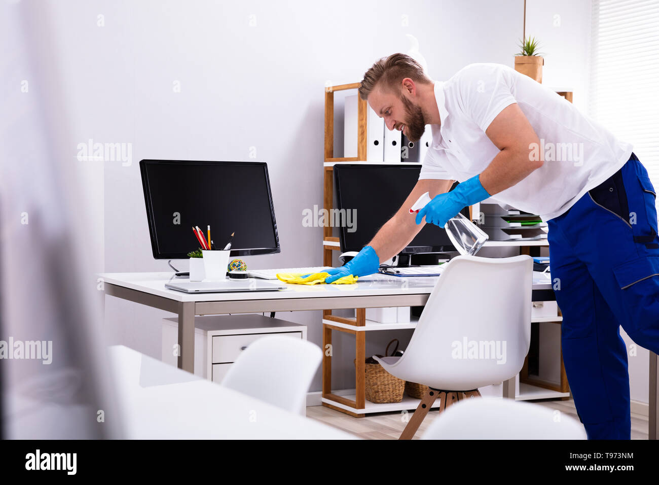 Janitor cleaning white desk in modern office Stock Photo Alamy