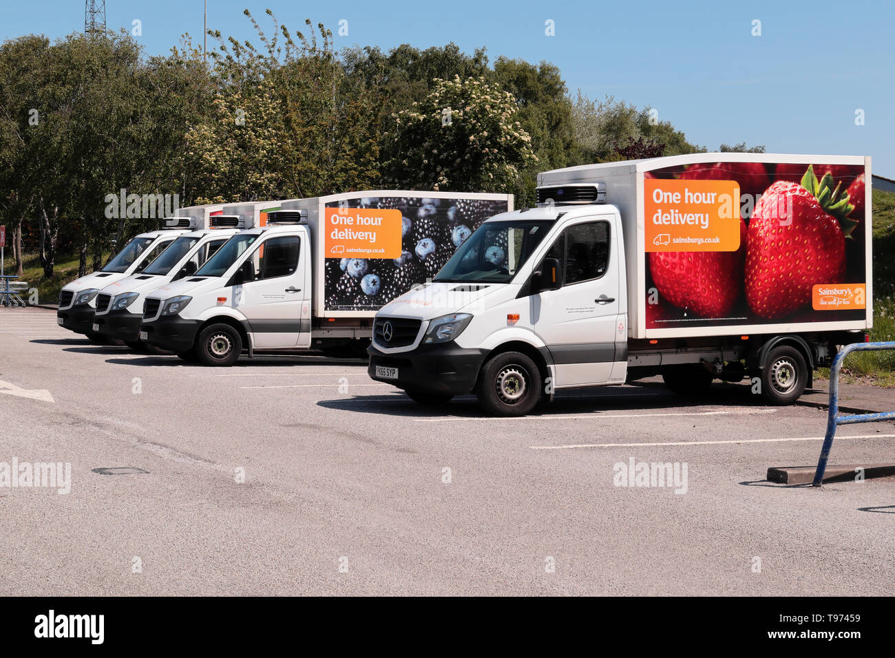 A line of four Sainsburys Home delivery Vans parked up in the store's car park. Stock Photo
