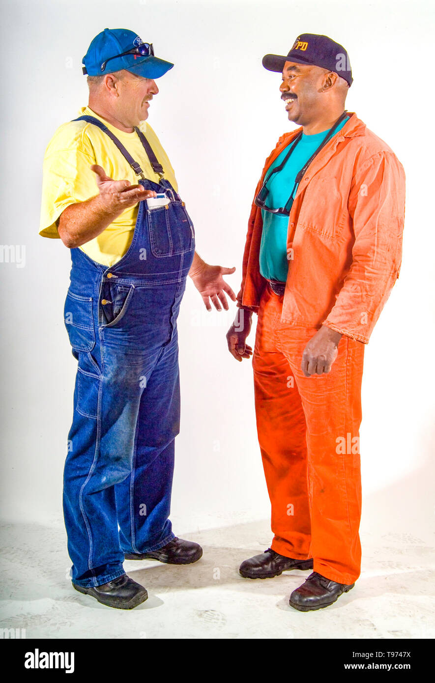 Caucasian and African American railroad maintenance workers converse cordially at the Los Angeles train yards. MODEL RELEASE Stock Photo