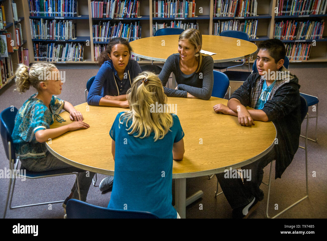 A junior high school counsellor meets with a multiethnic group of students in a San Clemente, CA, school library. Stock Photo