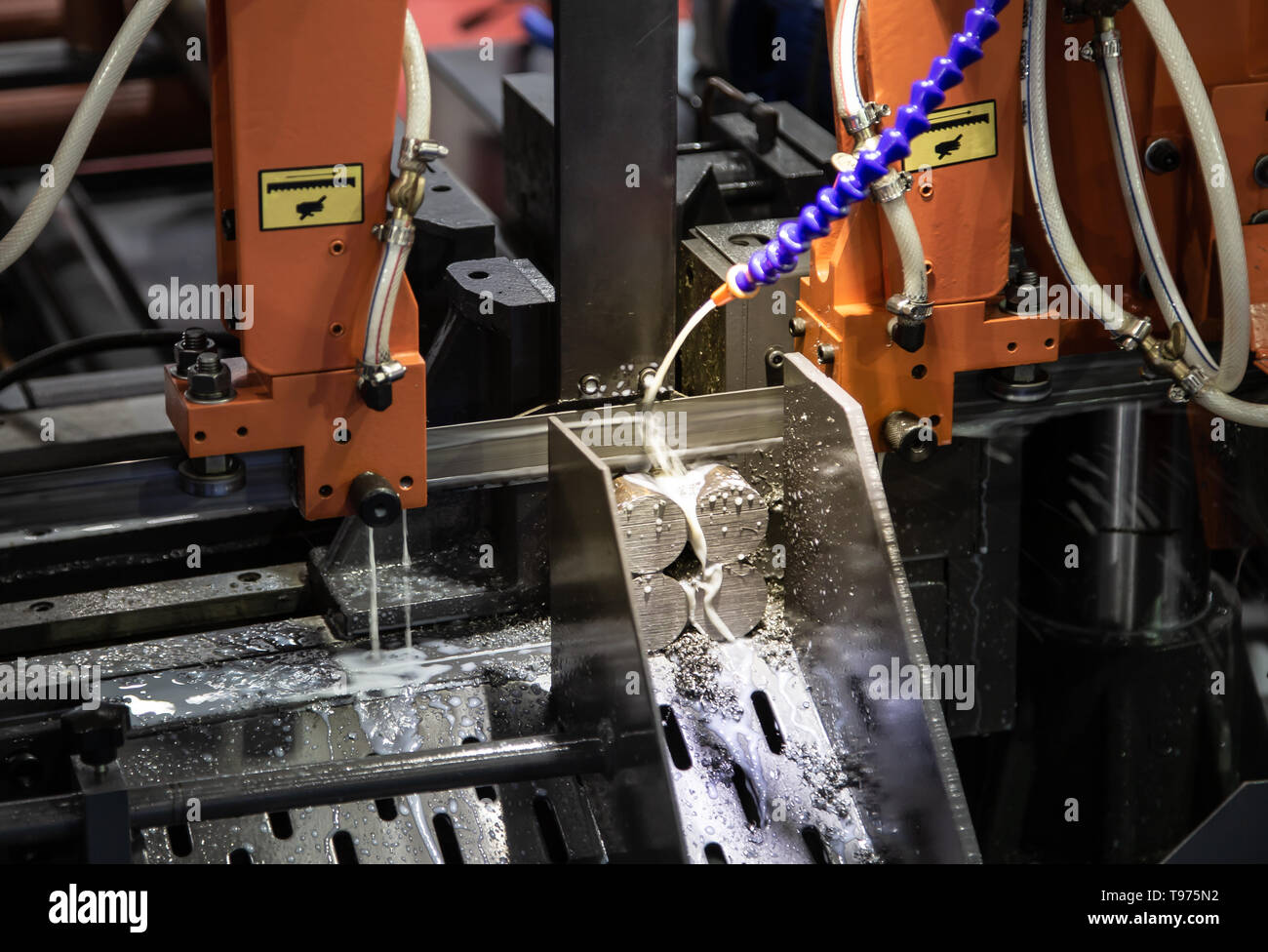 Band saw machine cutting metal rod and cooling with coolant Stock Photo